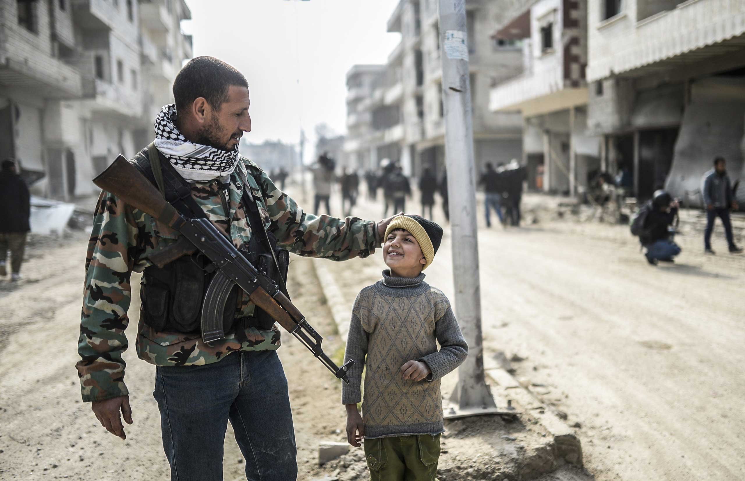 A Kurdish fighter walks with his child in the center of the Syrian border town of Kobani, Jan. 28, 2015.