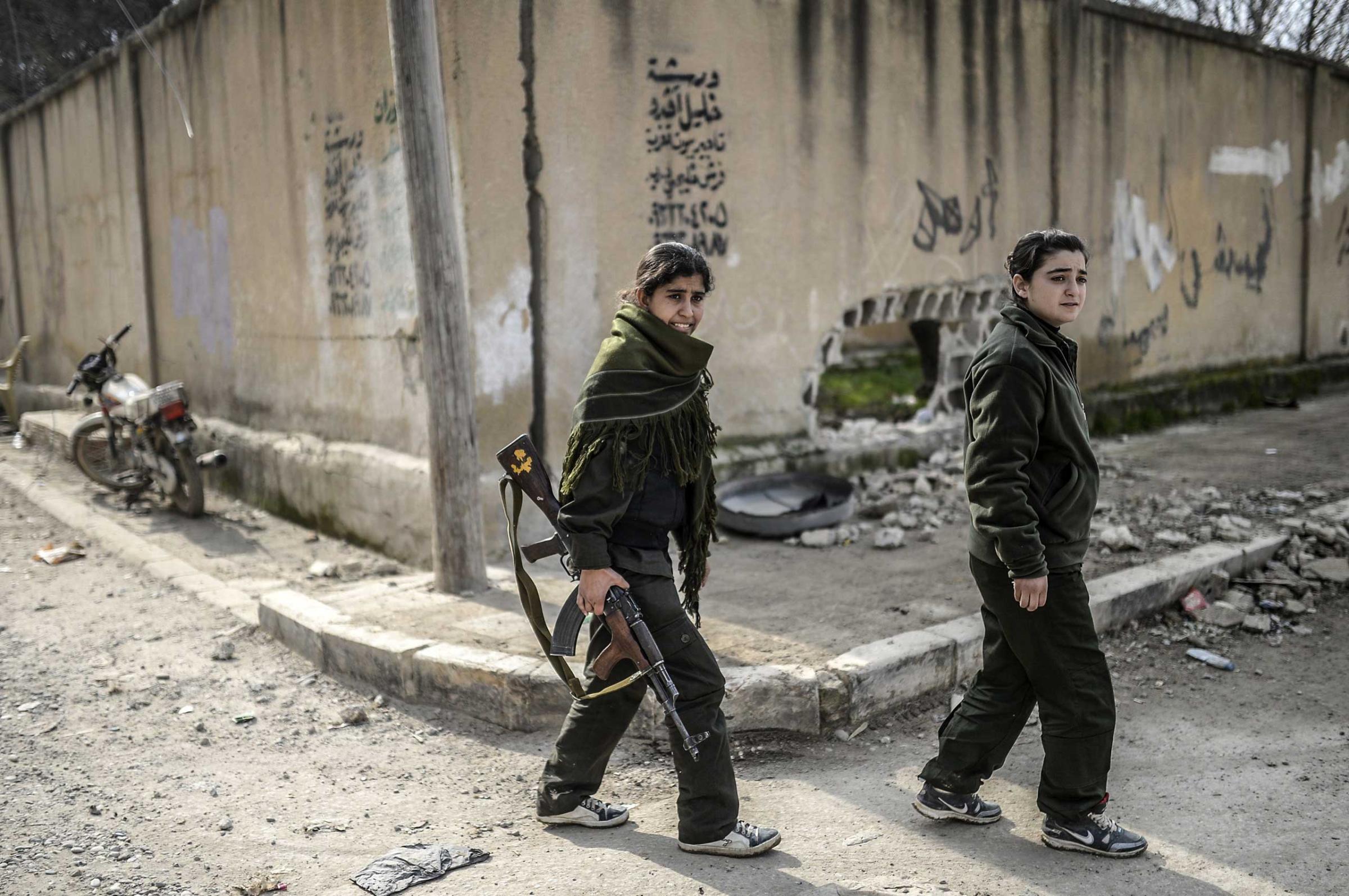 Kurdish fighters walk along a street in the center of the Syrian town of Kobani on Jan. 28, 2015.