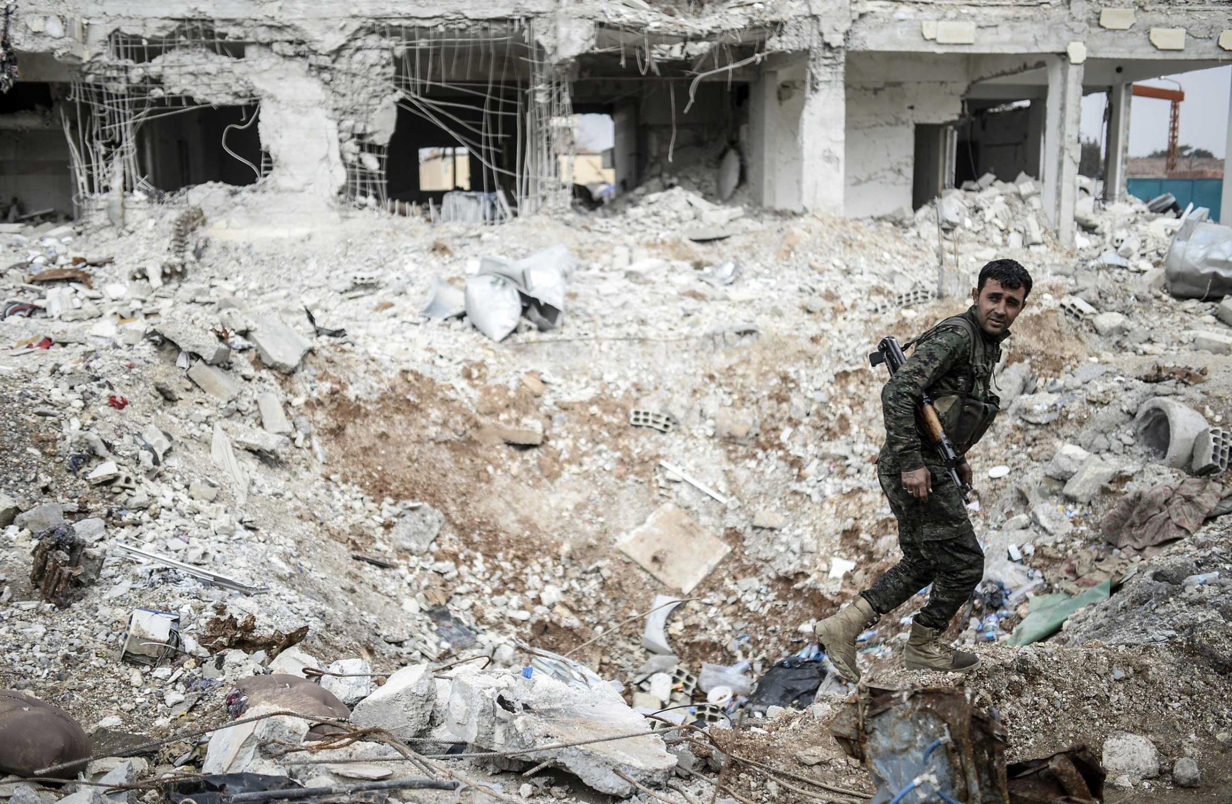 A Kurdish fighter walks through the wreckage of a building in the center of the Syrian town of Kobani on Jan. 28. 2015.