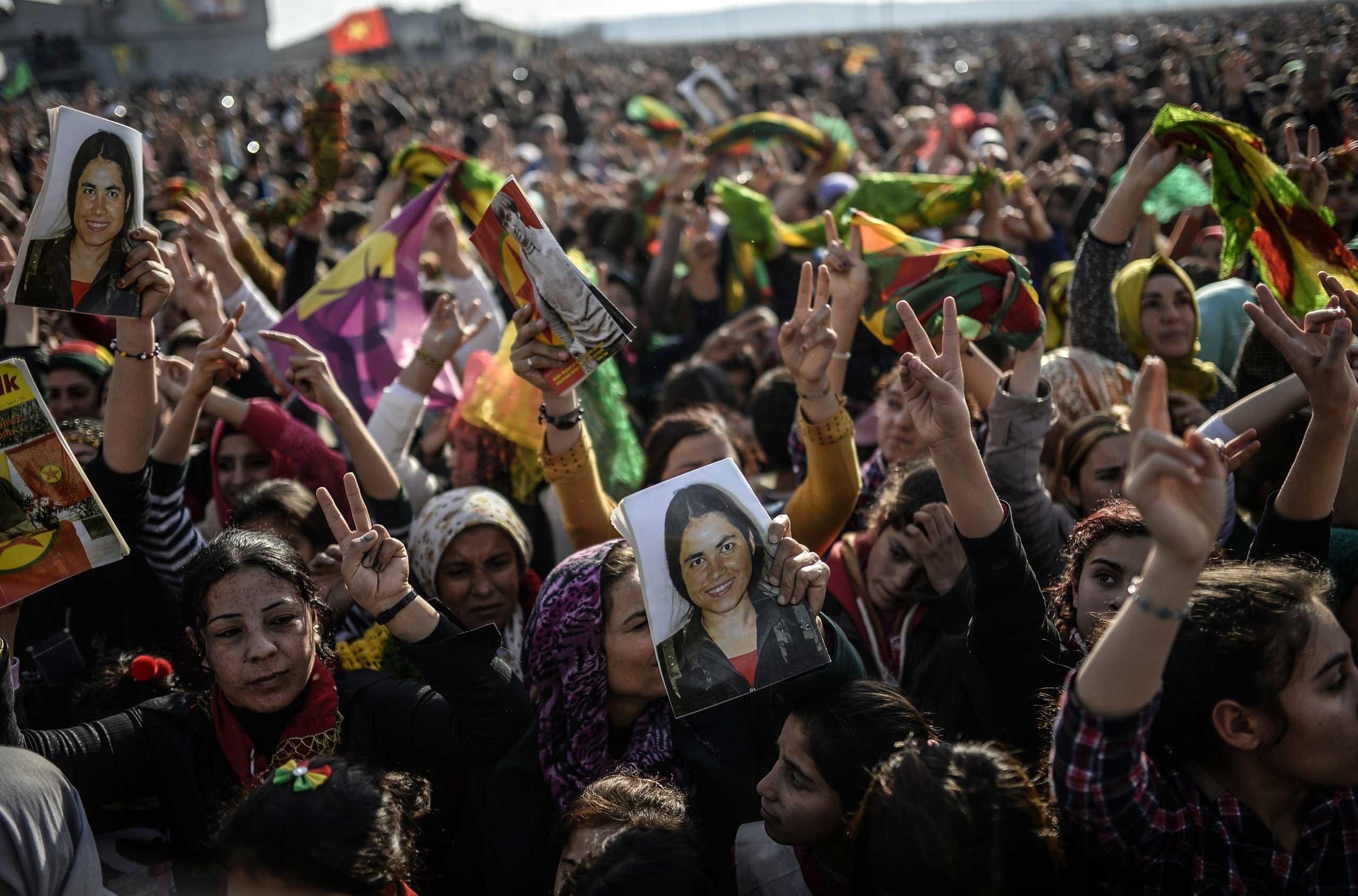 People hold a picture of a Kurdish fighter—killed during a battle with ISIS—during a celebration rally near the Turkish-Syrian border in Suruc, Turkey, on Jan. 27, 2015. (Bulent Kilic—AFP/Getty Images)