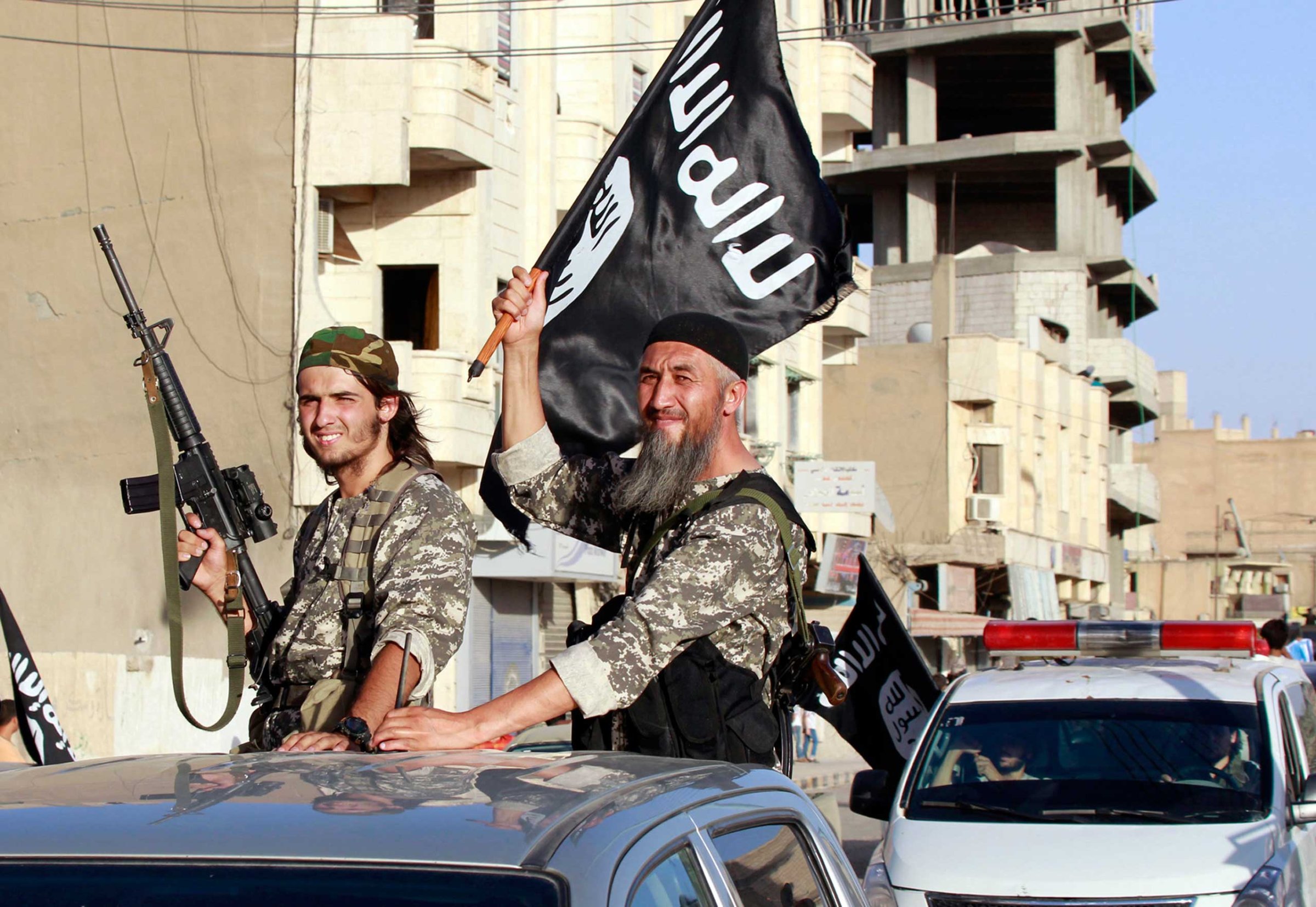 Militant Islamist fighters wave flags as they take part in a military parade along the streets of Syria's northern Raqqa province June 30, 2014.