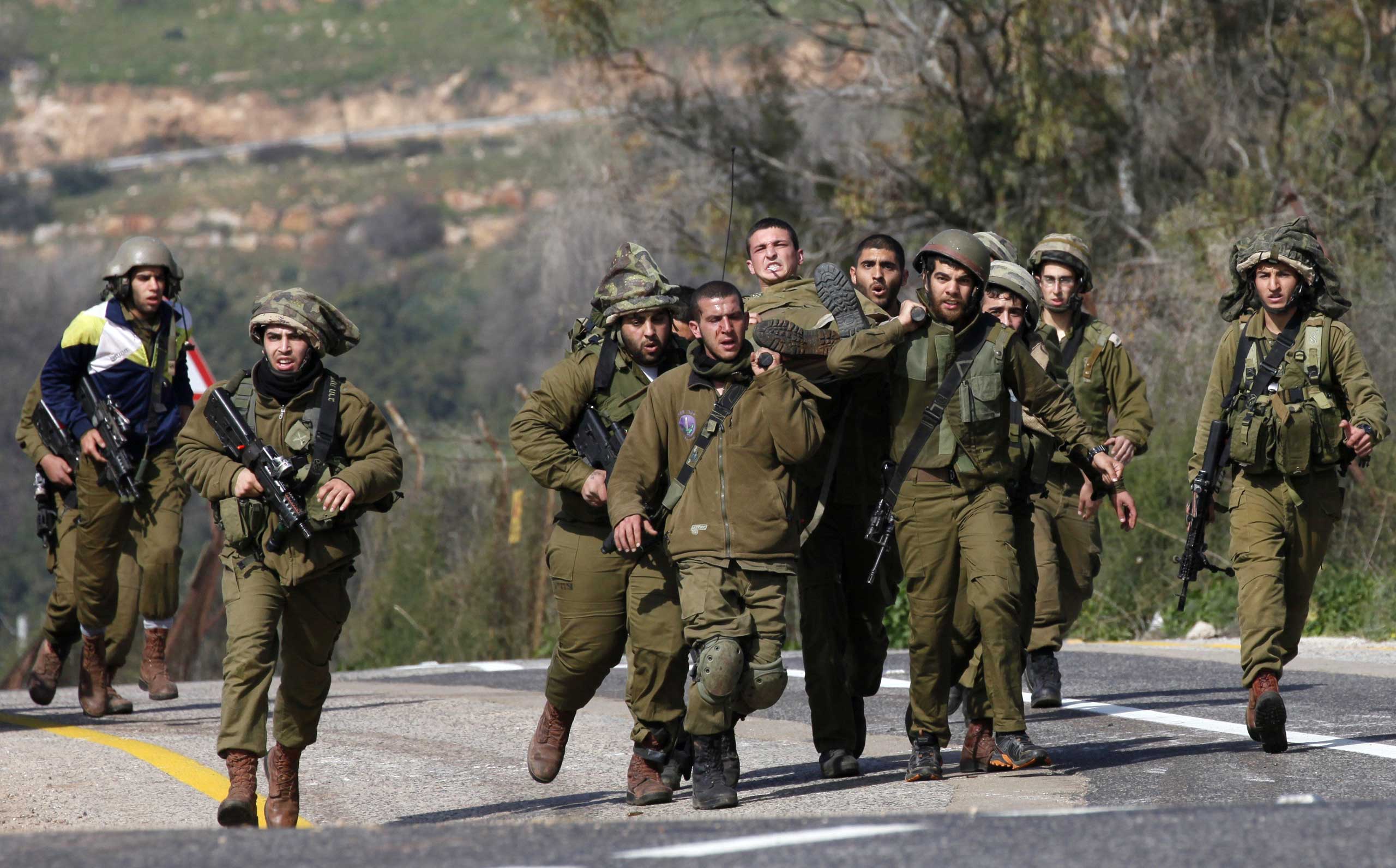 Israeli soldiers carry an injured comrade after an anti-tank missile hit an army vehicle in an occupied area on the border with Lebanon on Jan. 28, 2015.