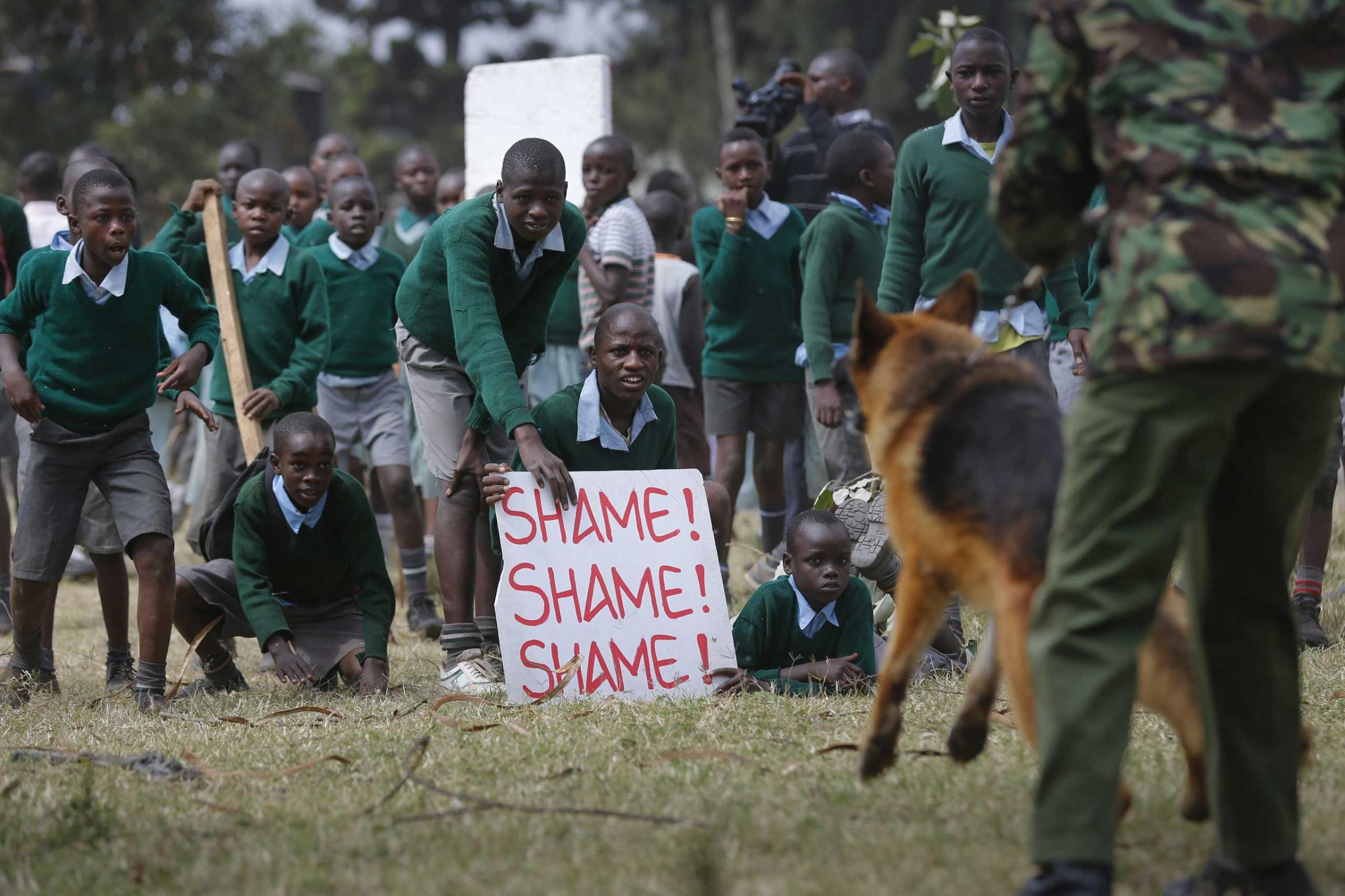 School children face off against a police dog handler during a protest against alleged land grabbing at Langata Road Primary School in Nairobi, Jan. 19 2015.