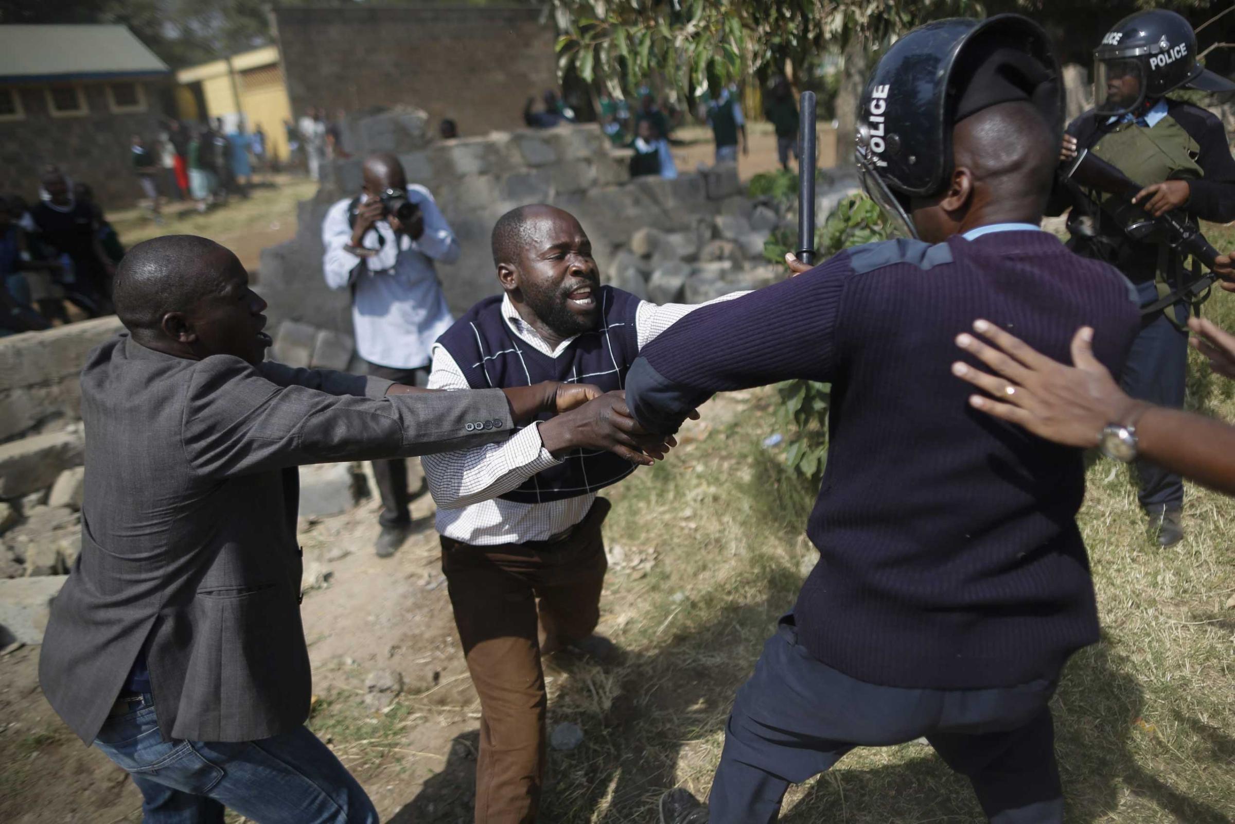 A protester clashes with a police officer during a protest against alleged land grabbing at Langata Road Primary School in Nairobi, Jan. 19, 2015.