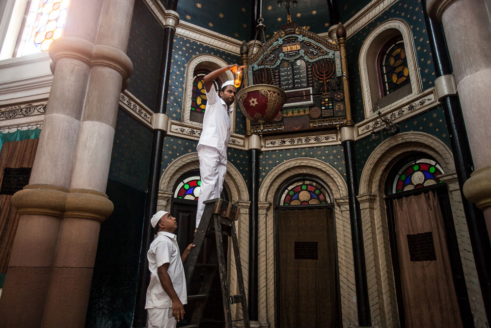 Nrusingha Charan Swain and Anwar Khan, one of the four caretakers of the Maghen David synagogue, lighting the Ner Tamid inside the ark. Nrusingha is Hindu and Anwar is Muslim.