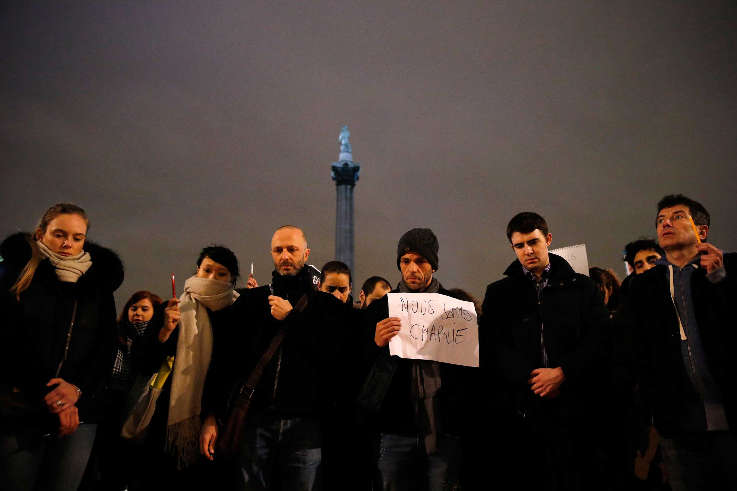 People raise pens and signs during a vigil to pay tribute to the victims of a shooting by gunmen at the Paris headquarters of the satirical weekly <i>Charlie Hebdo</i> at Trafalgar Square in London on Jan. 7, 2015 (Suzanne Plunkett—Reuters)