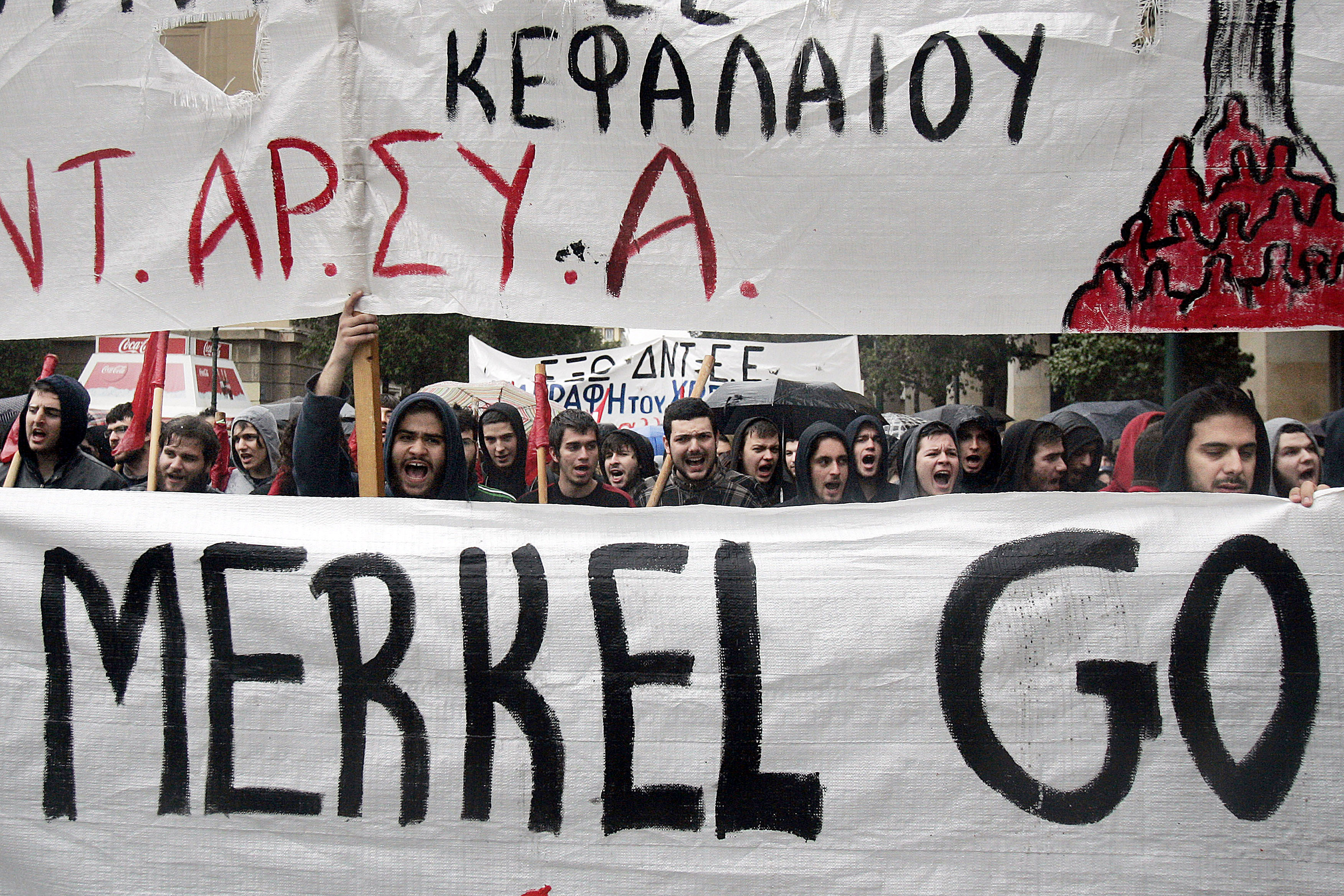 Protesters hold a banner as they march during a demonstration against the visit of Germany's Chancellor Angela Merkel on April 11, 2014 in Athens.