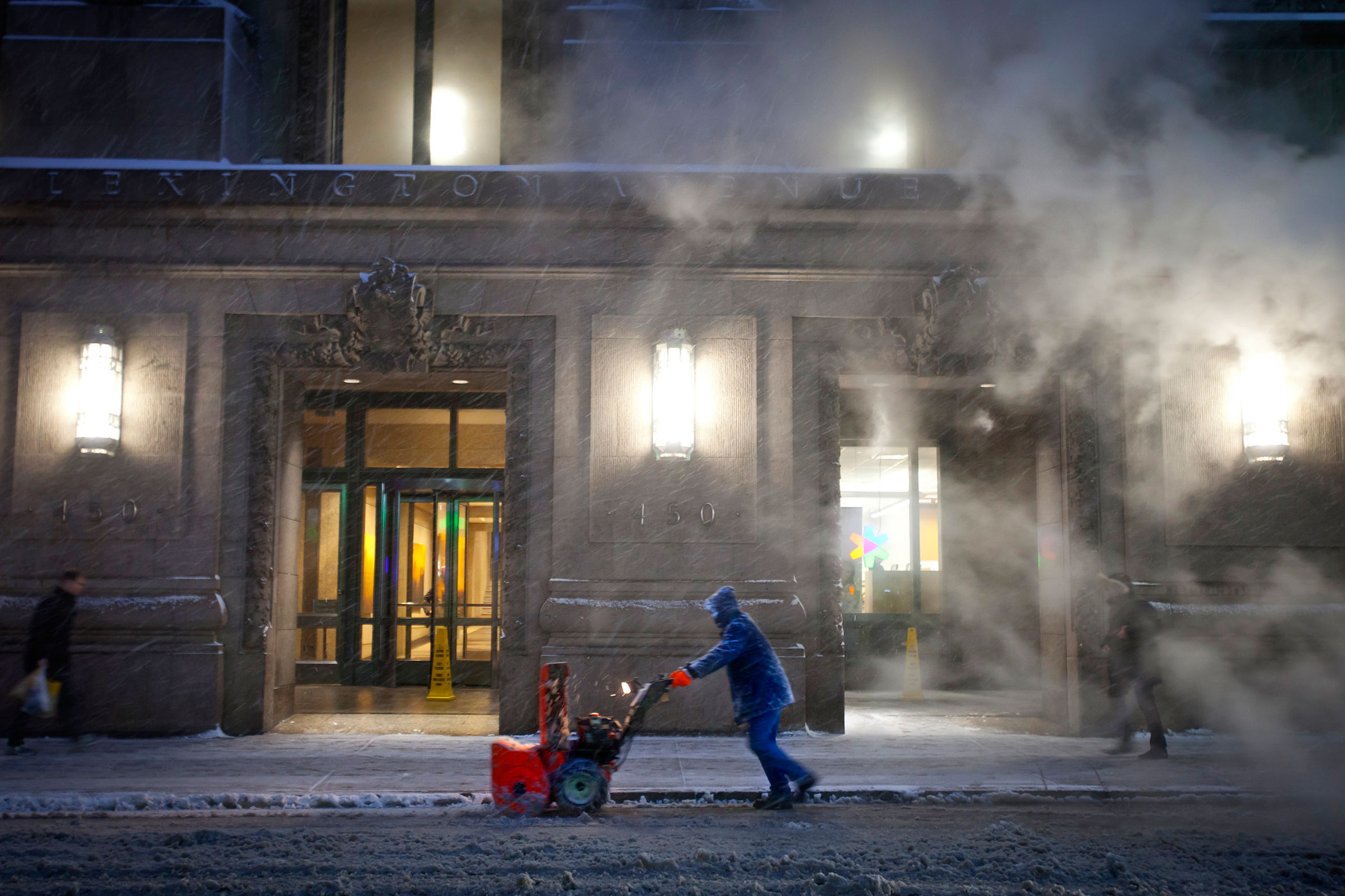 A worker pushes a snow blower down Lexington Avenue near Grand Central Terminal as it snows in the Manhattan borough of New York