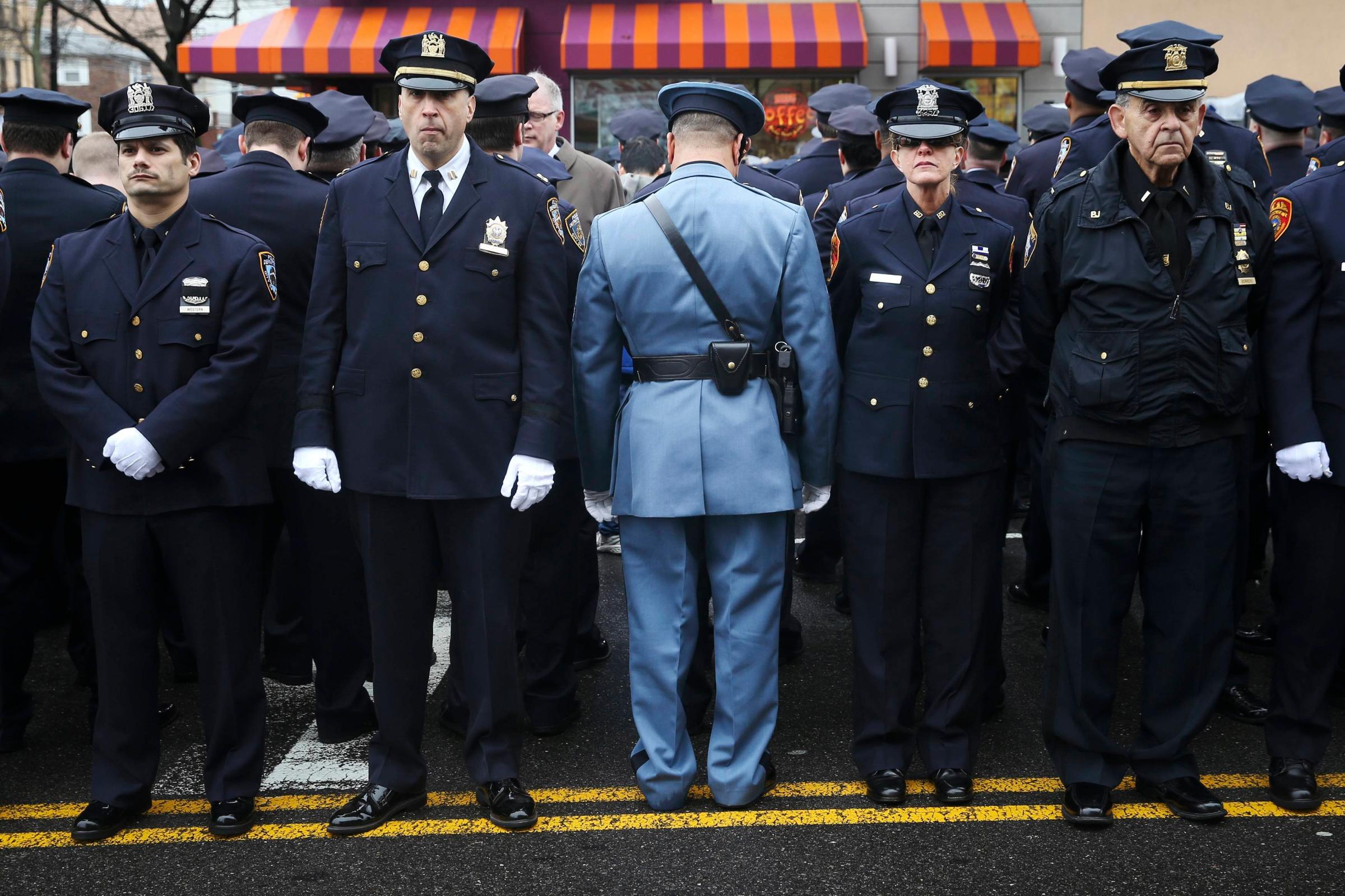 Law enforcement officers stand, with some turning their backs, as New York City Mayor Bill de Blasio speaks on a monitor outside the funeral for NYPD officer Wenjian Liu in the Brooklyn borough of New York