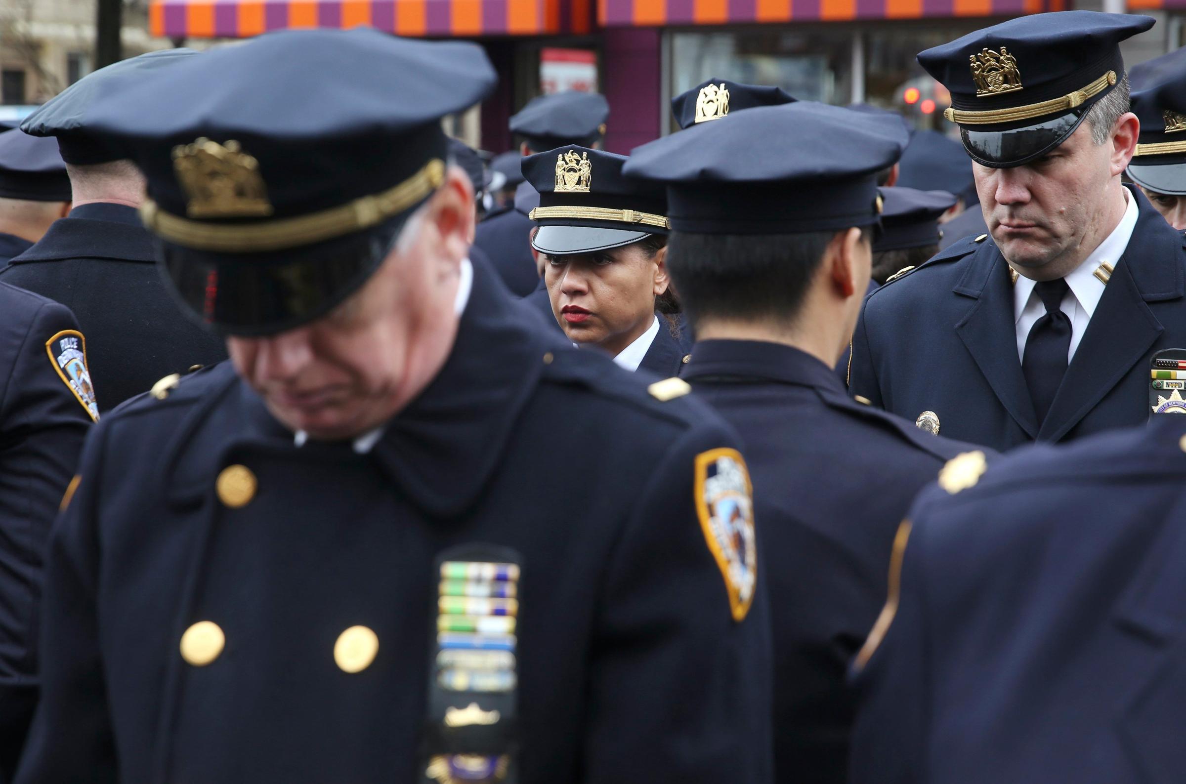 Law enforcement officers stand, with some turning their backs, as New York City Mayor Bill de Blasio speaks on a monitor outside the funeral for NYPD officer Wenjian Liu in the Brooklyn borough of New York