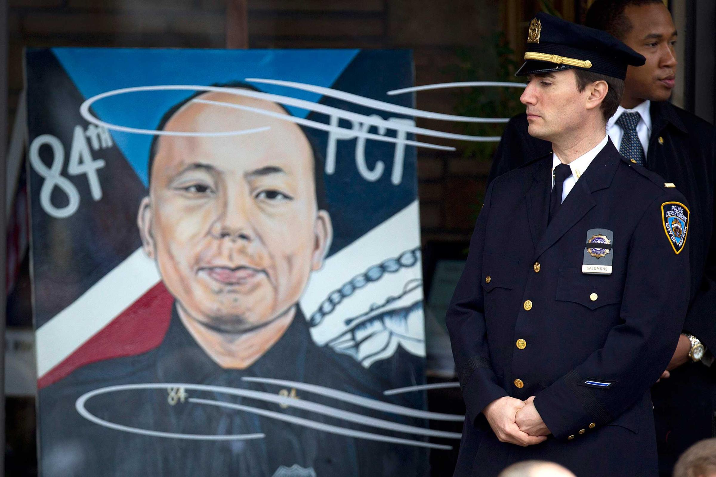 Policeman stands next to an image of slain New York Police Department officer Wenjian Liu during his funeral in the Brooklyn borough of New York