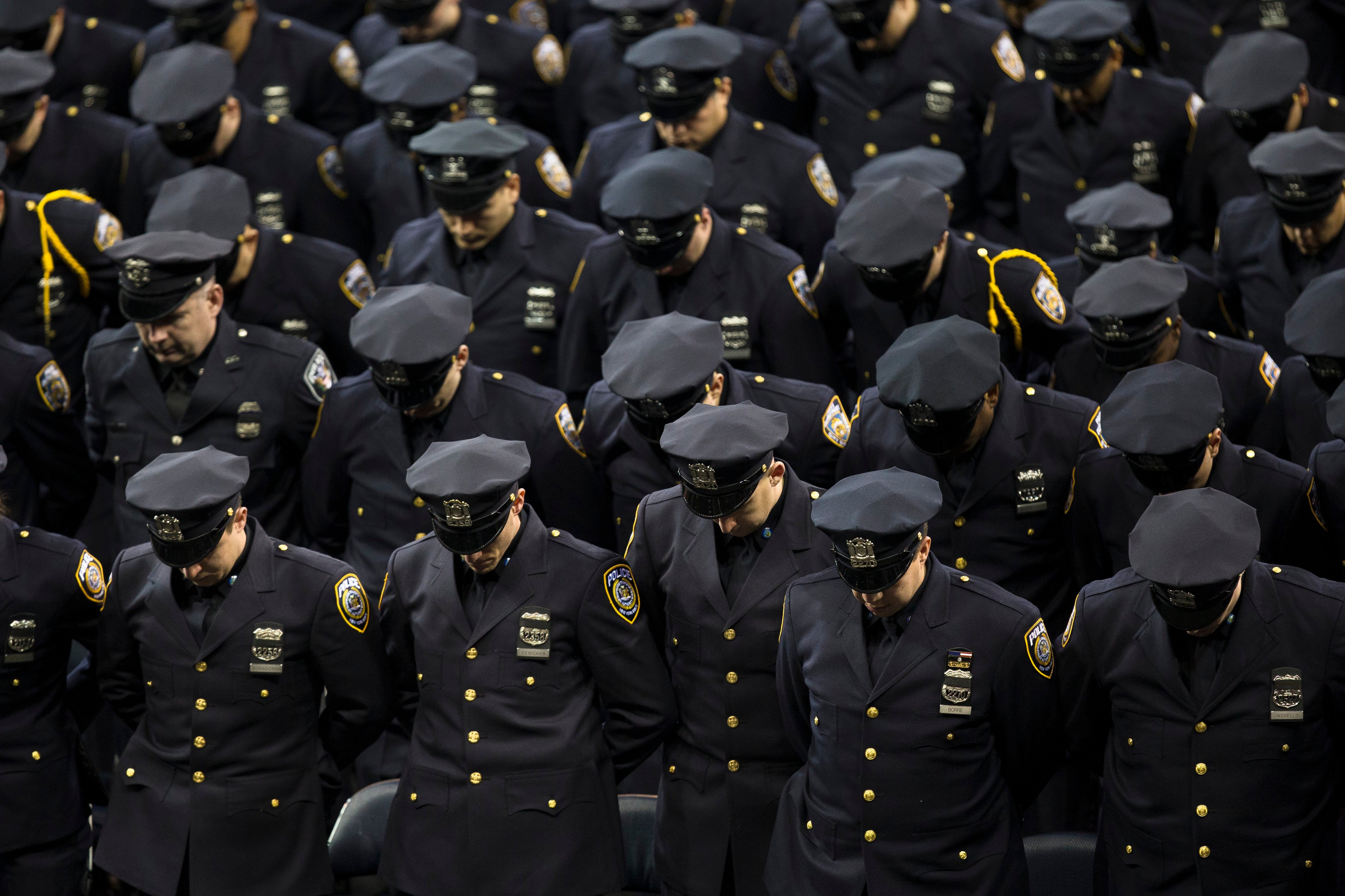New recruits bow their heads for a moment of silence during a New York Police Academy graduation ceremony at Madison Square Garden in New York City on Dec. 29, 2014. (John Minchillo—AP)