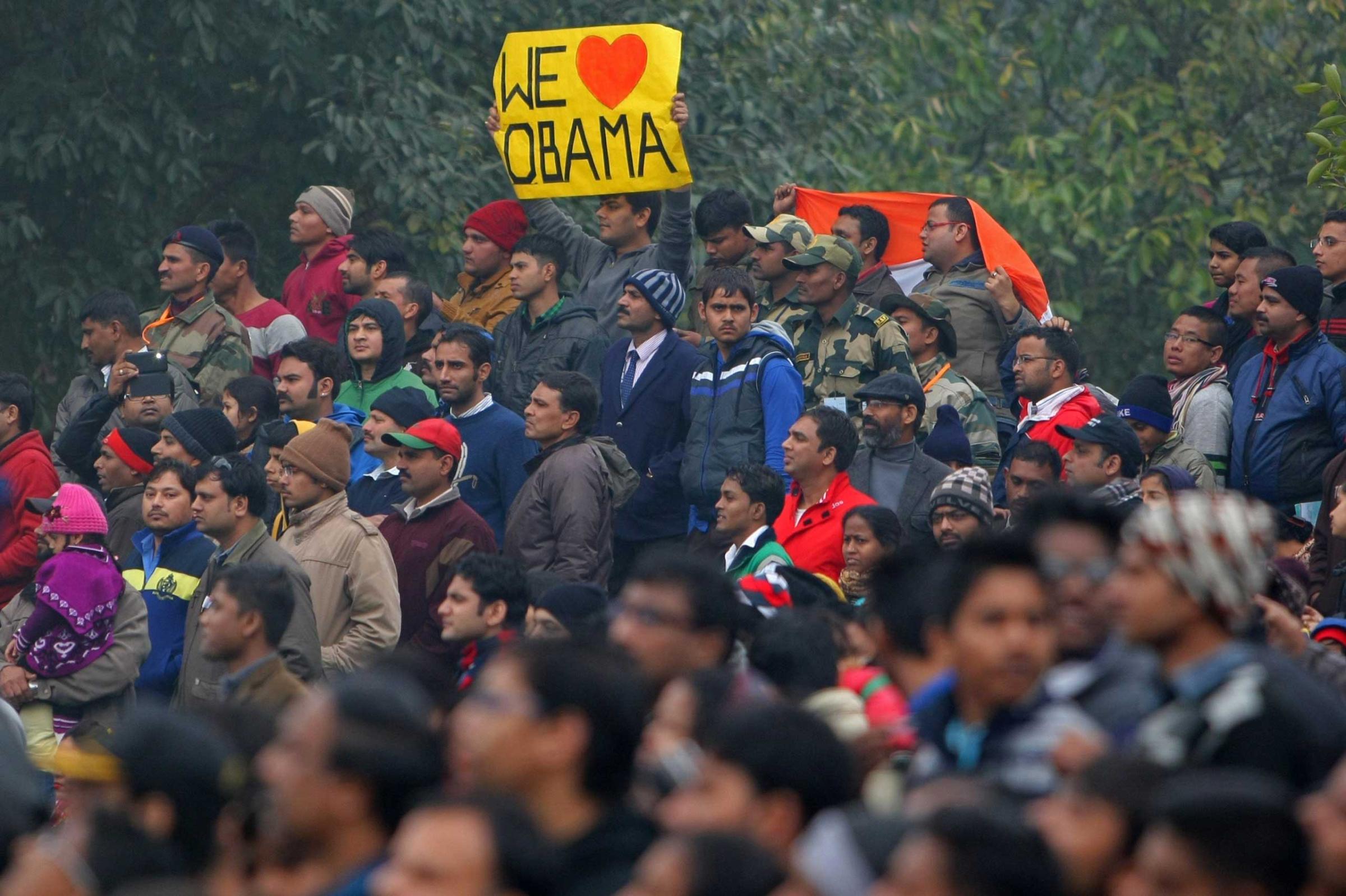 A spectator holds a placard that reads "We Love Obama" as the motorcade of President Obama departs following the conclusion of the country's Republic Day Parade in New Delhi on Jan. 26, 2015.