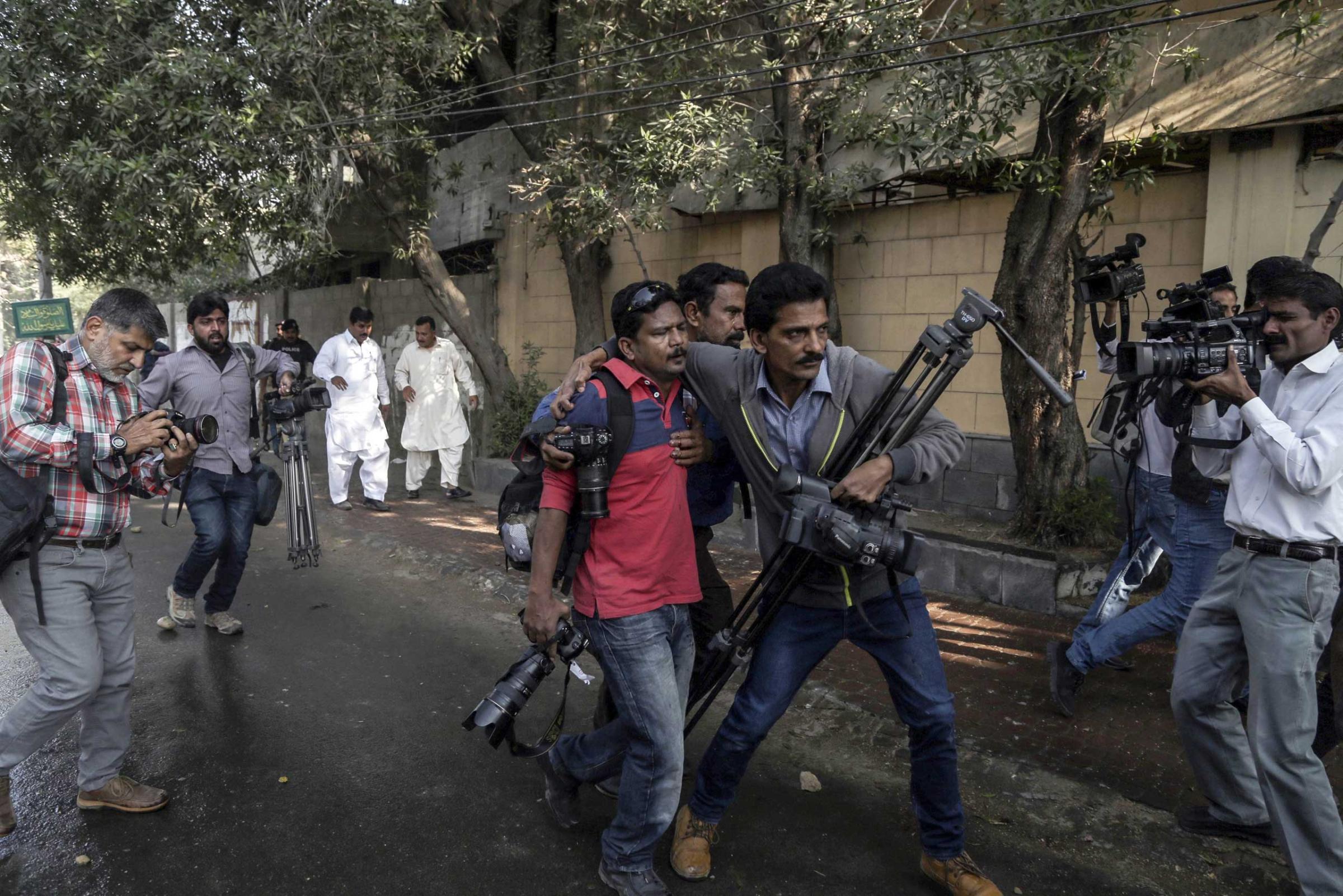 Pakistani journalists help a colleague who was injured in clashes between police and the supporters of Islamic political party Jamat-e-Islami during a protest against the French magzine 'Charlie Hebdo' for publishing the caricatures of the prophet Muhammad, in Karachi, Pakistan on Jan. 16, 2015.