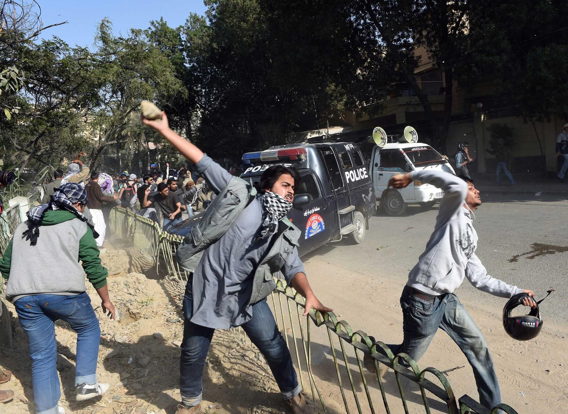 Pakistani activists of the Jamaat-e-Islami religious party throw stones toward riot police during a protest against the printing of satirical sketches of the Prophet Muhammad by French magazine Charlie Hebdo in Karachi, Pakistan on Jan.16, 2014.