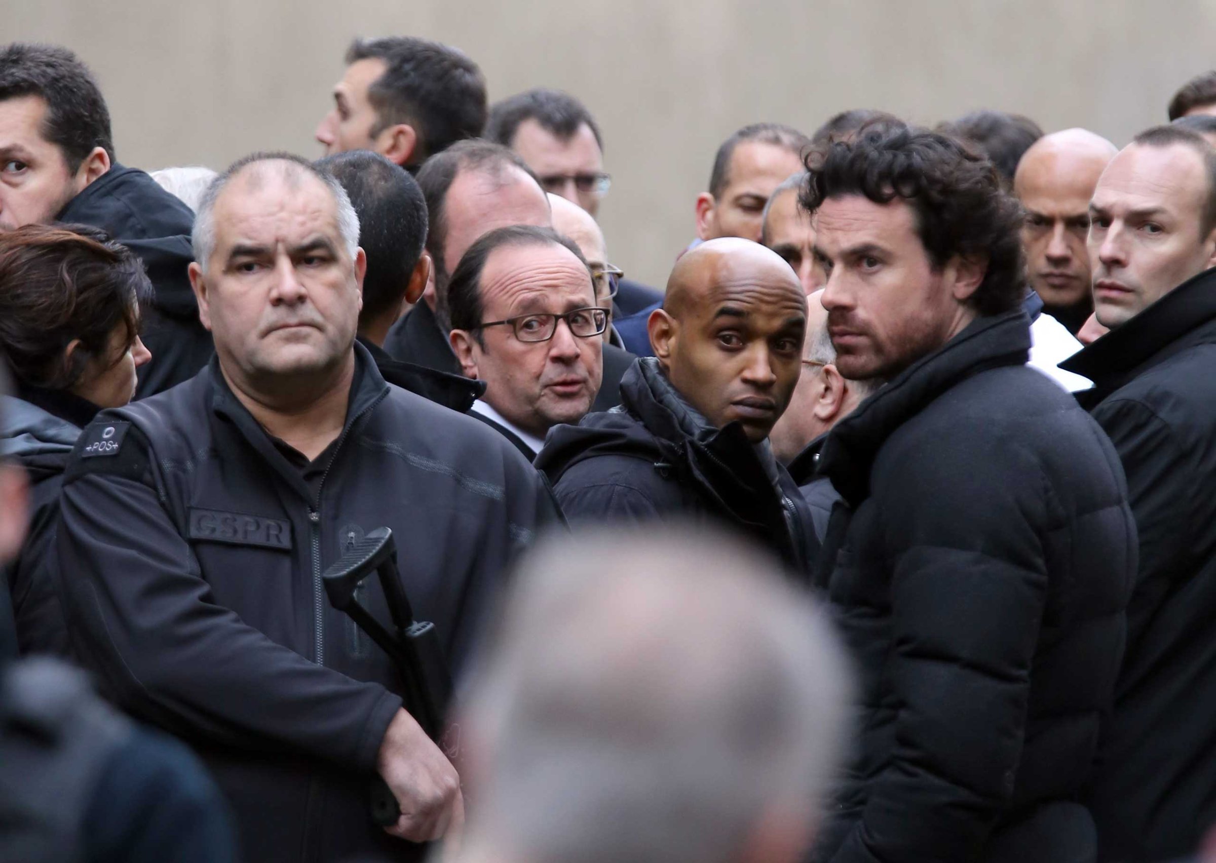 President Francois Hollande, center, flanked with security forces arrives outside the French satirical newspaper Charlie Hebdo's office, in Paris, Jan. 7, 2015.