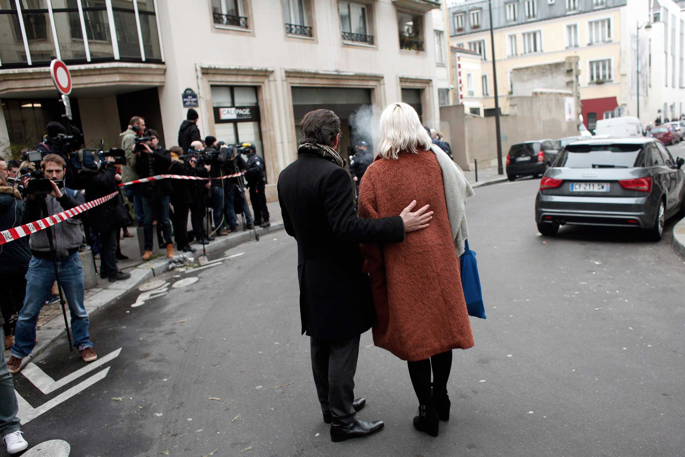 People stand outside the French satirical newspaper Charlie Hebdo's office after a shooting, in Paris, Jan. 7, 2015.