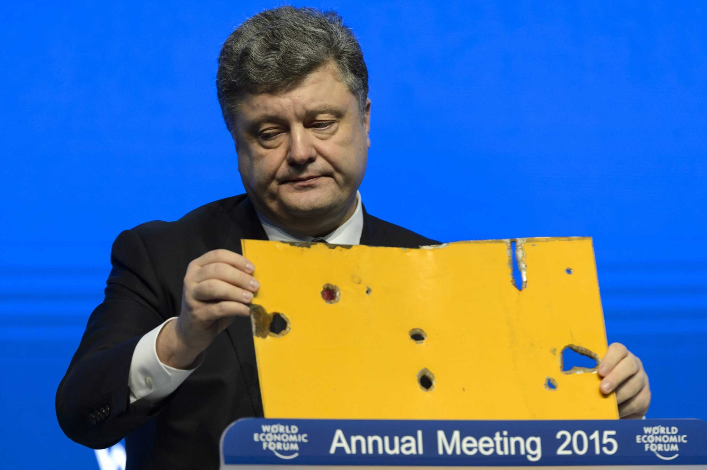The president of Ukraine Petro Poroshenko speaks with a piece of a damaged passenger bus hit by a shell that killed twelve passengers and injured 13 others at a Ukrainian military checkpoint near the town of Volnovakha, during a panel session on the first day of the 45th Annual Meeting of the World Economic Forum, WEF, in Davos, Jan. 21, 2015.