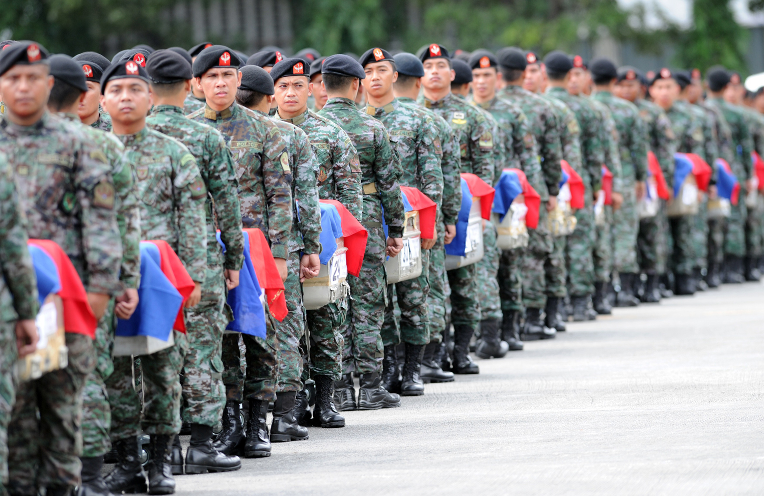 Philippine police commandos stand at attention next to the flag-draped coffins of their slain comrades shortly after arriving at a military base in Manila on Jan. 29, 2015 (Ted Aljibe — AFP/Getty Images)