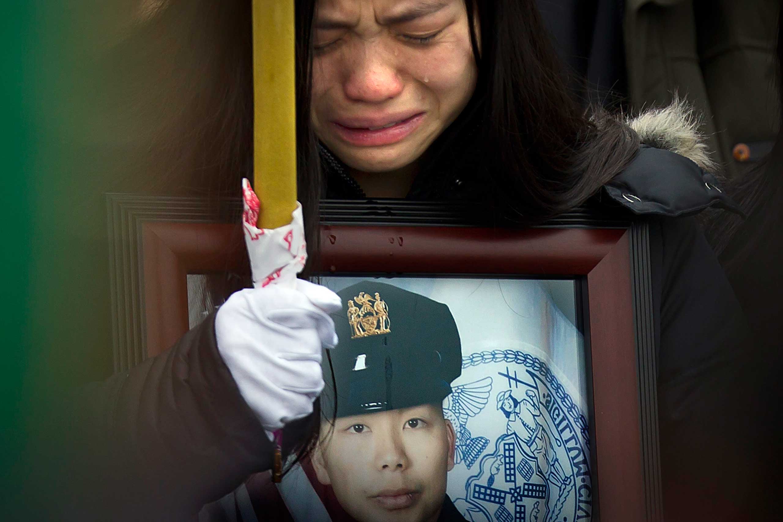 Jan. 4, 2015. Tears shed by widow Pei Xia Chen fall onto the frame of a portrait of her slain husband, New York Police Department officer Wenjian Liu, as his casket departs his funeral in New York.