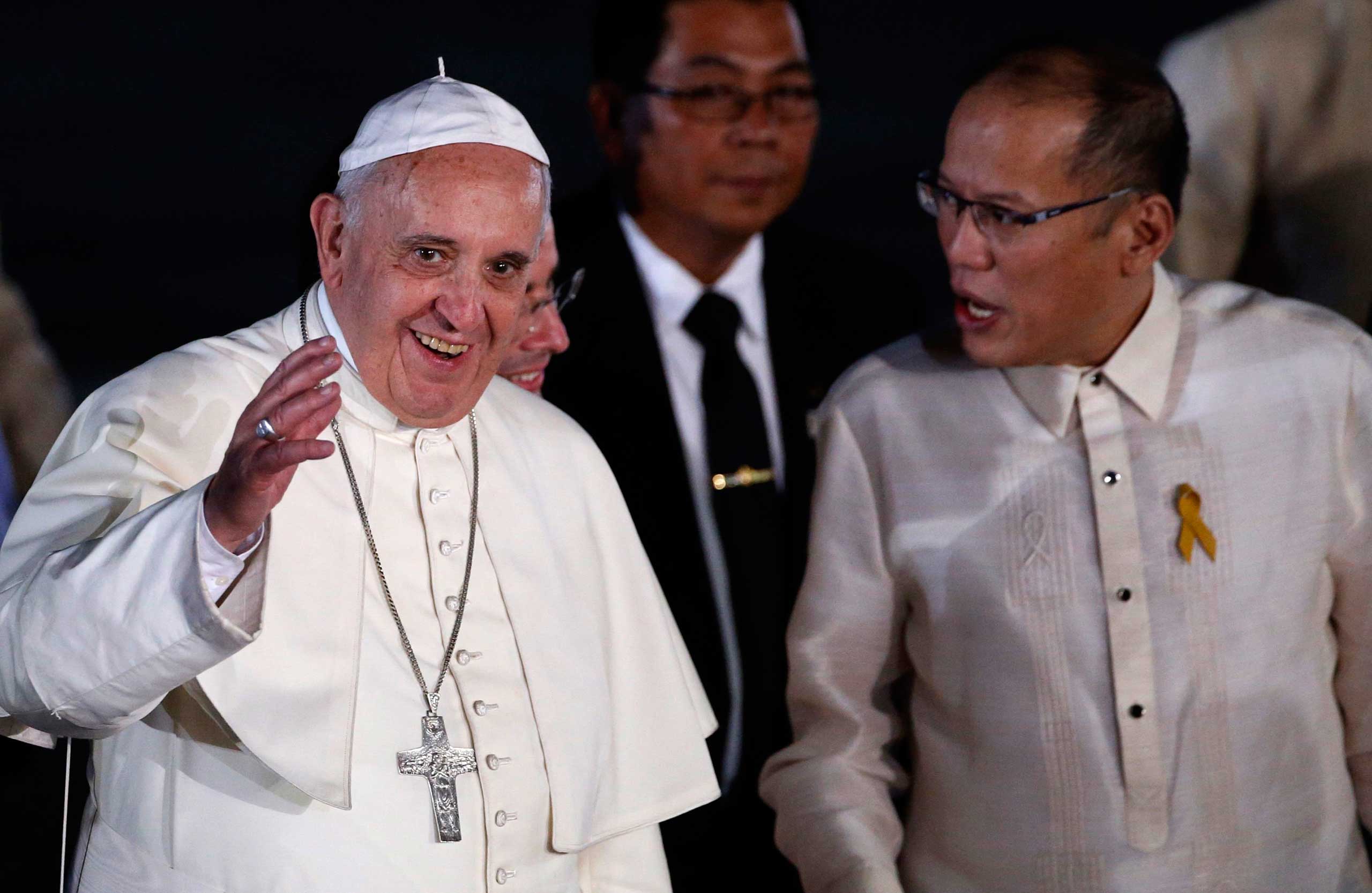 Pope Francis waves to the crowd next to President Aquino upon his arrival at Villamor Air Base in Manila