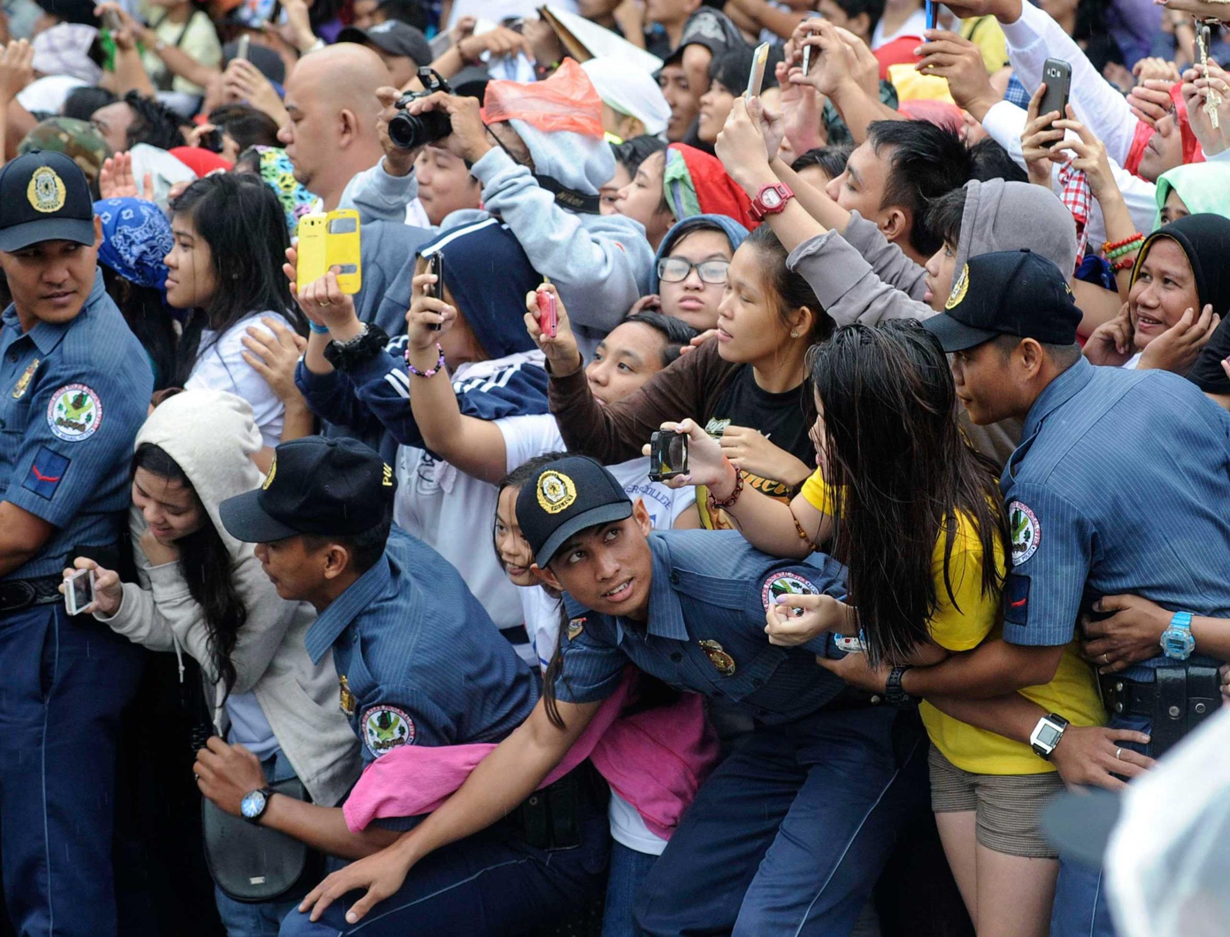 Members of the Philippine National Police prevent well-wishers from moving forward as Pope Francis' motorcade passes by in Manila, Jan. 18, 2015.
