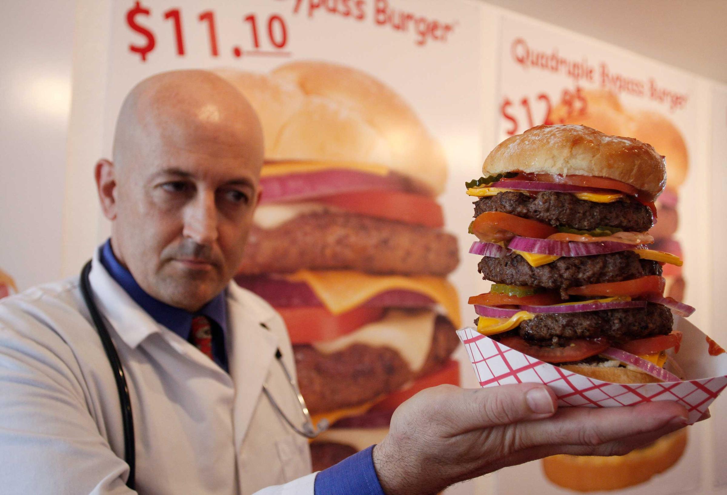 Heart Attack Grill owner Jon poses with a quadruple bypass cheese burger in Chandler, Arizona