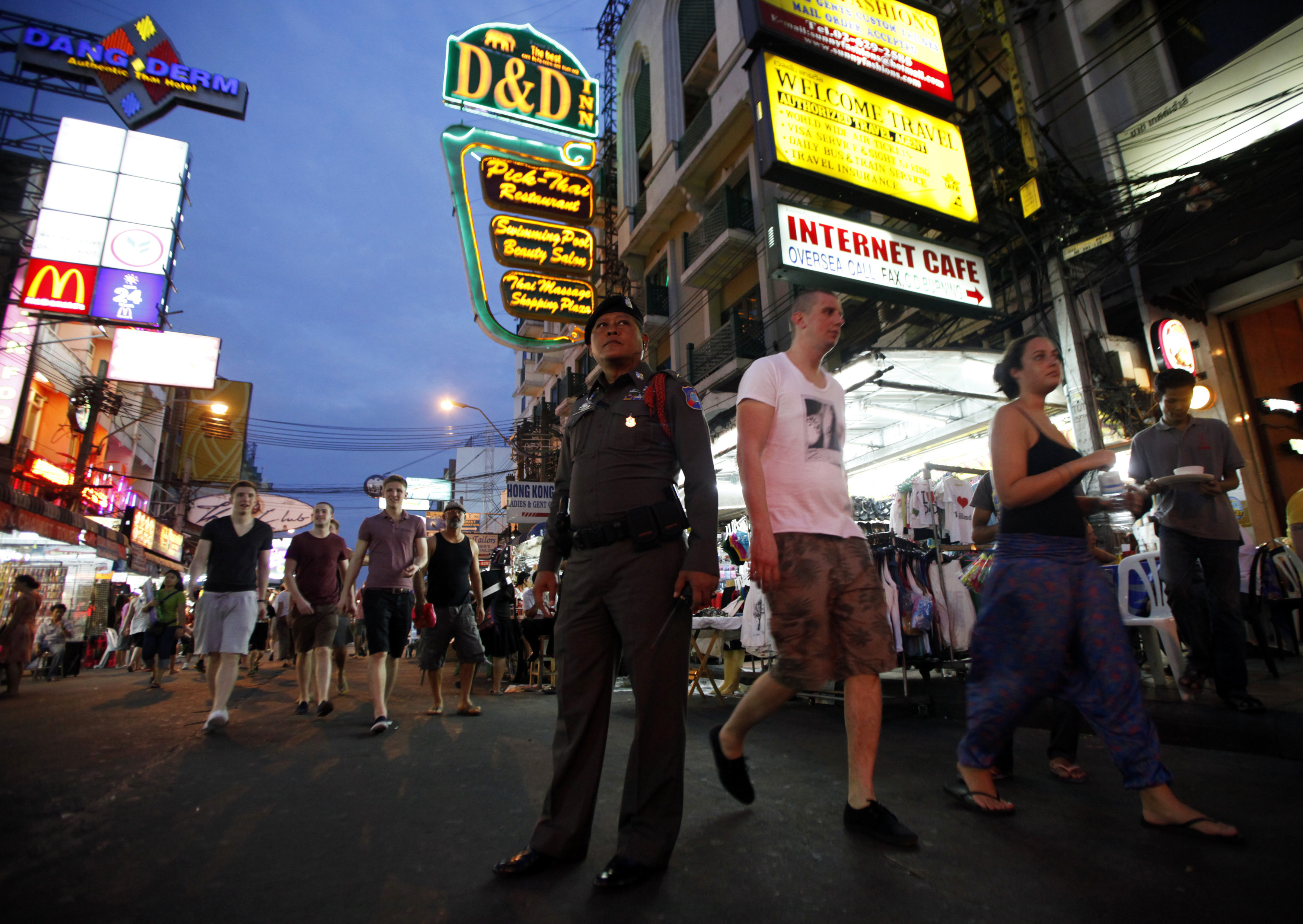 A tourist policeman stands guard as tourists walk along Khao San road in Bangkok