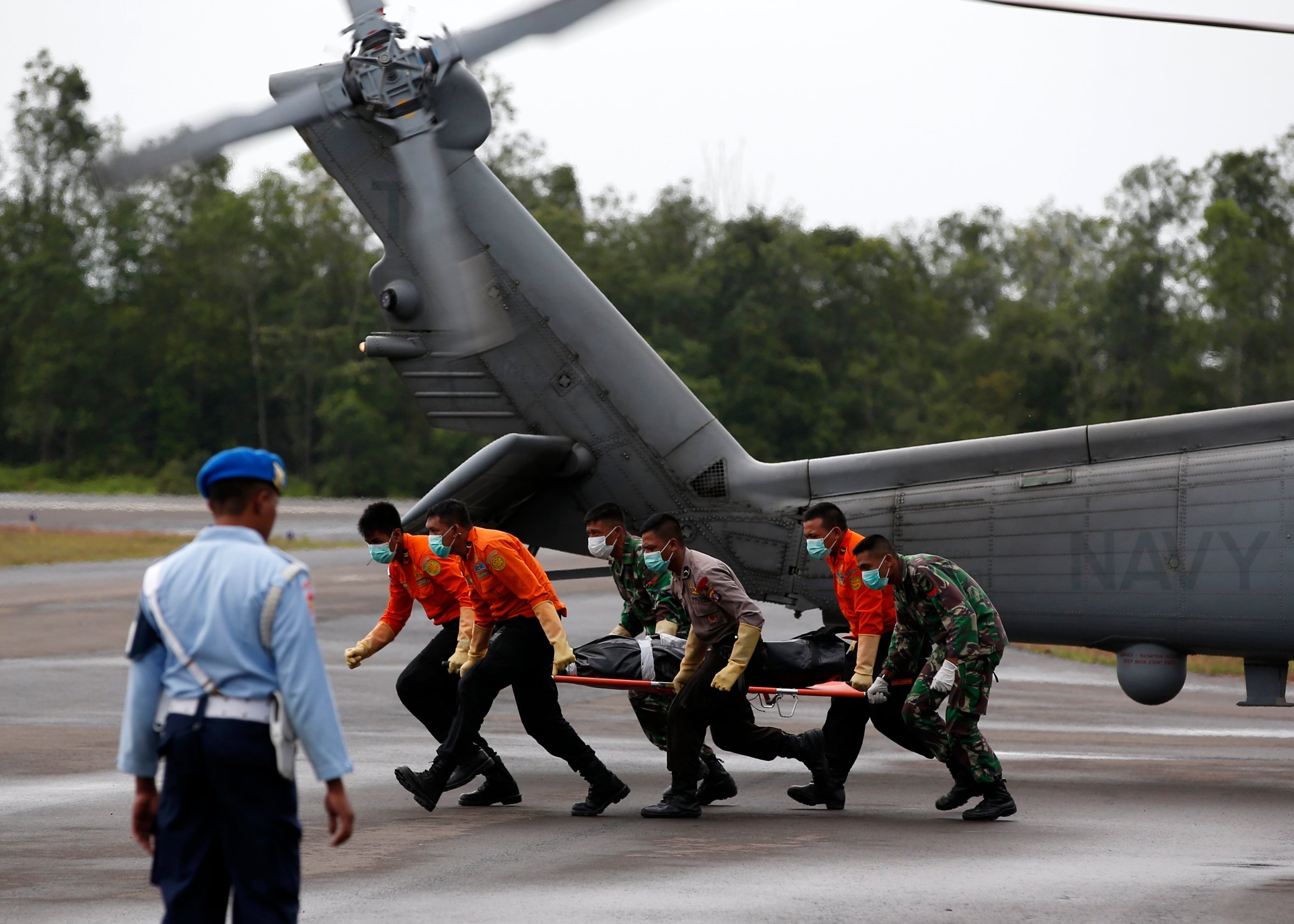 The body of an AirAsia QZ8501 passenger is carried to an ambulance after being transported from a ship by a U.S. Navy helicopter from the USS Sampson at the airbase in Pangkalan Bun