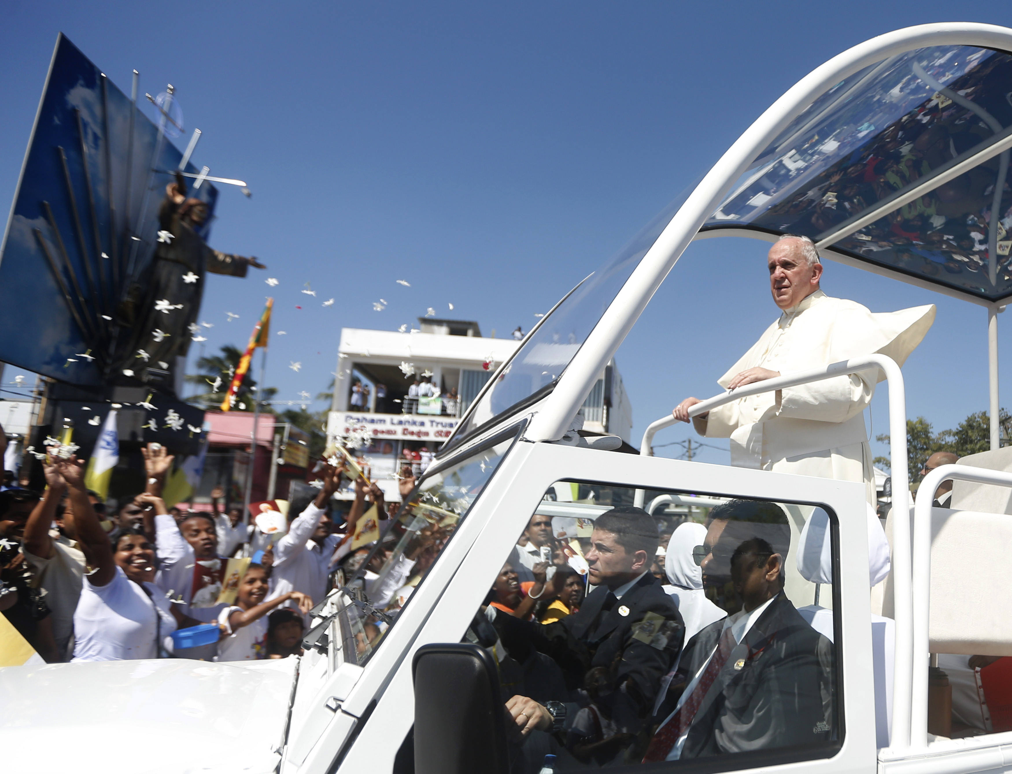 Pope Francis stands on his vehicle as devotees gather on the road to see him after he arrived at the Colombo airport