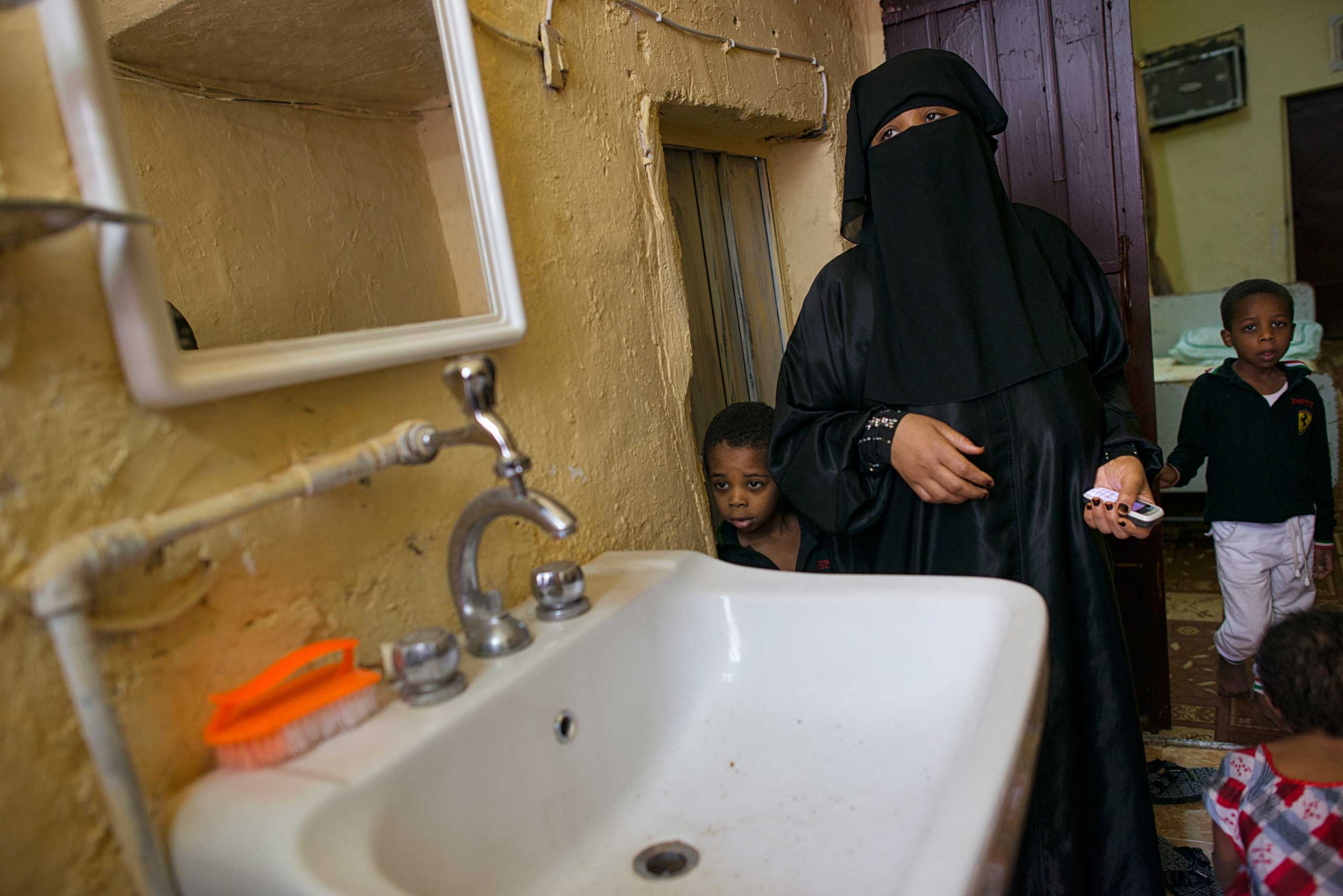 Matara stands with her two boys next to a sink without water in her home in South Riyadh.