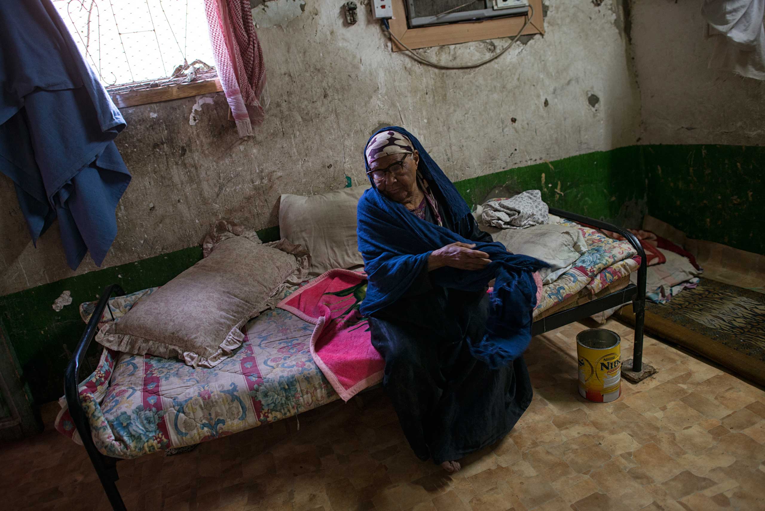 Selma Saleh, an impoverished Saudi woman, sits on her bed in her home in South Riyadh.