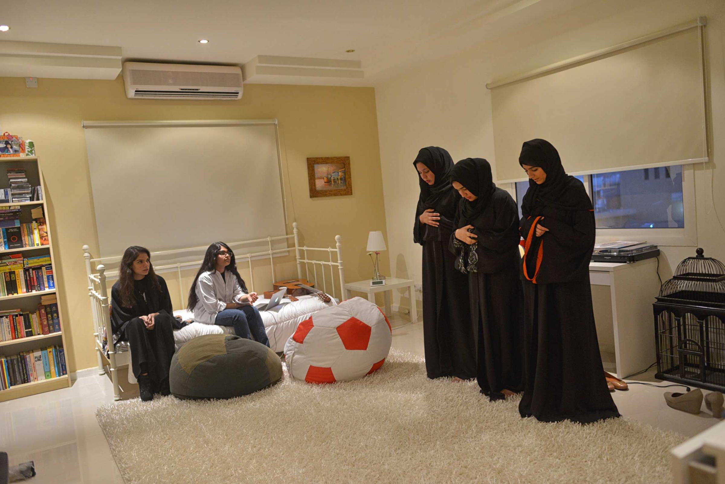 Young Saudi women pray in a friend's home before going out to dinner in Riyadh, Saudi Arabia, February 25, 2013.  Though statistics are difficult to confirm, youth unemployment and poverty are on the rise in Saudi Arabia.  While society is increasingly open to women in the workforce, there are still limited jobs in which women and men can work side by side.  There are a great number of highly educated Saudis who can not find work suitable for their qualifications.  (Credit: Lynsey Addario/ VII)