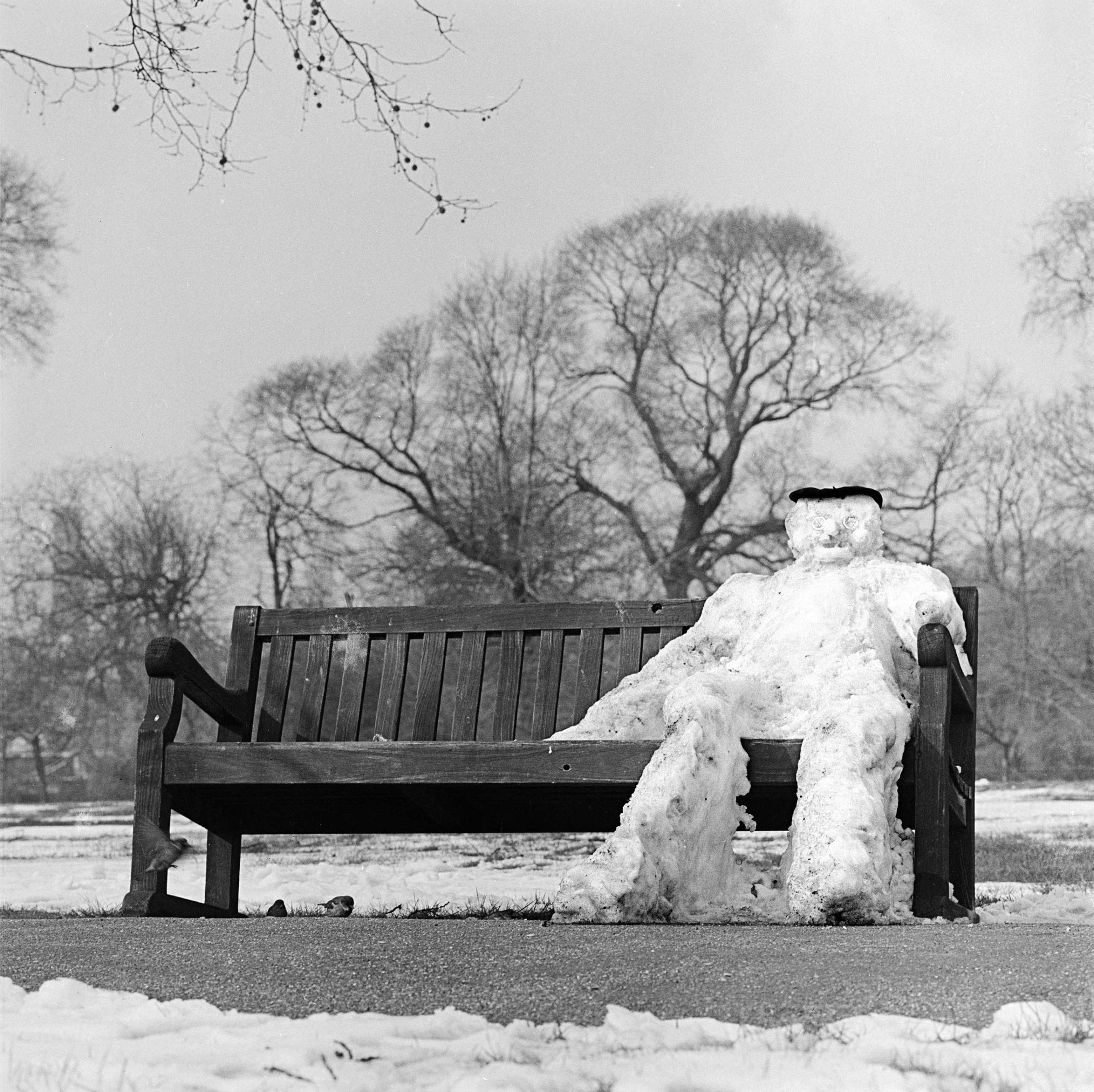 REGENTS PARK, London. A snowman sitting on a park bench.