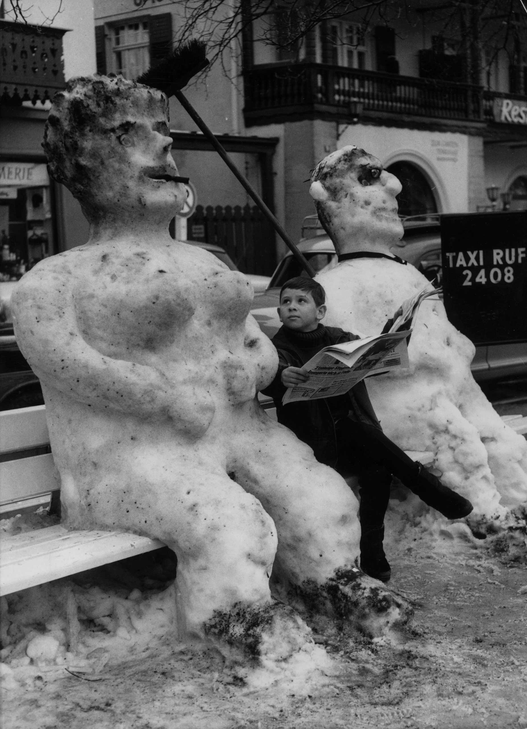 A boy sitting between a giant snowman and snowwoman in a street in Garmisch-Partenkirchen, Bavaria, on Jan. 24, 1966