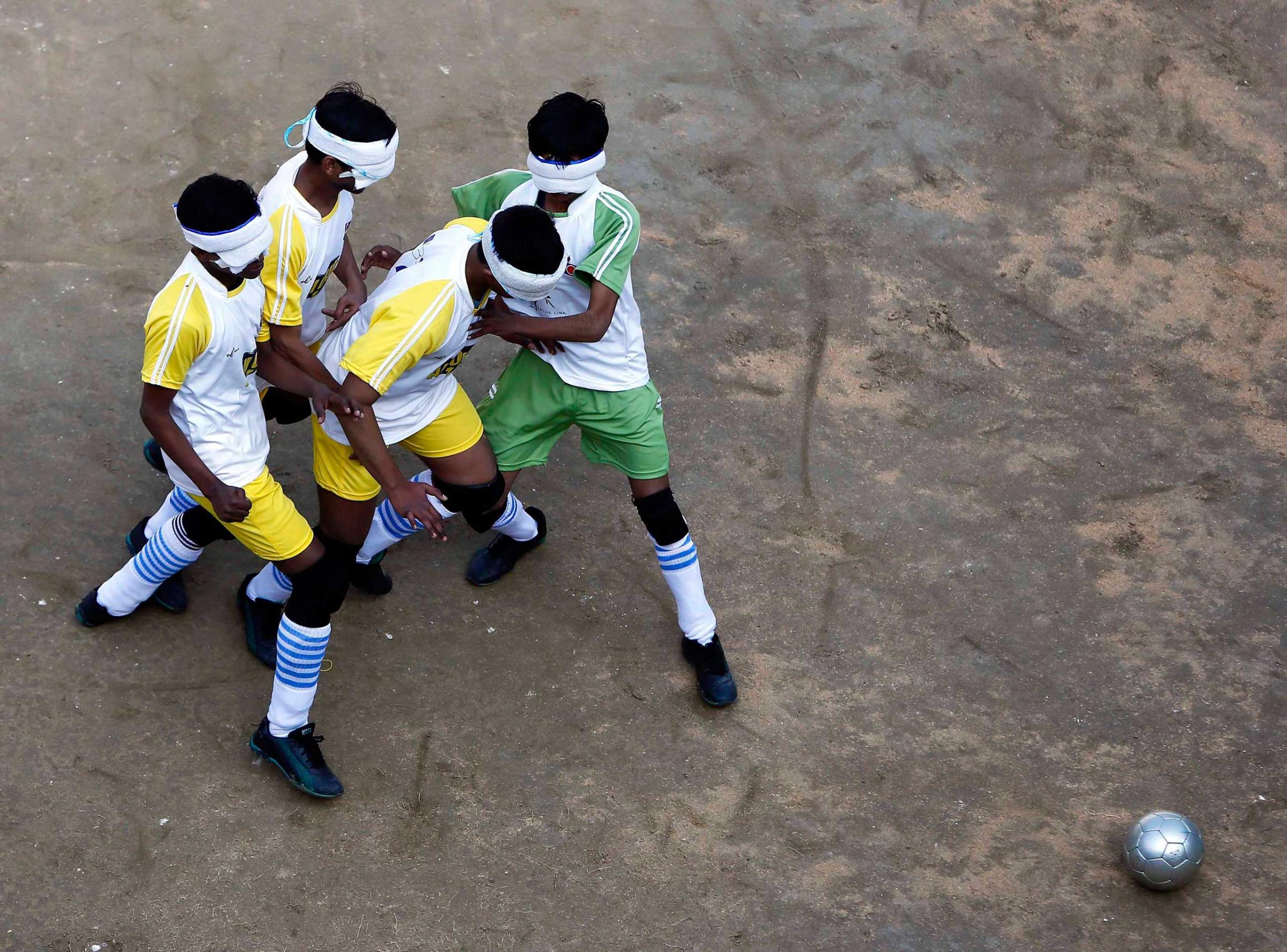 Visually impaired students of a school for the blind fight for the ball during a soccer match inside their school in New Delhi