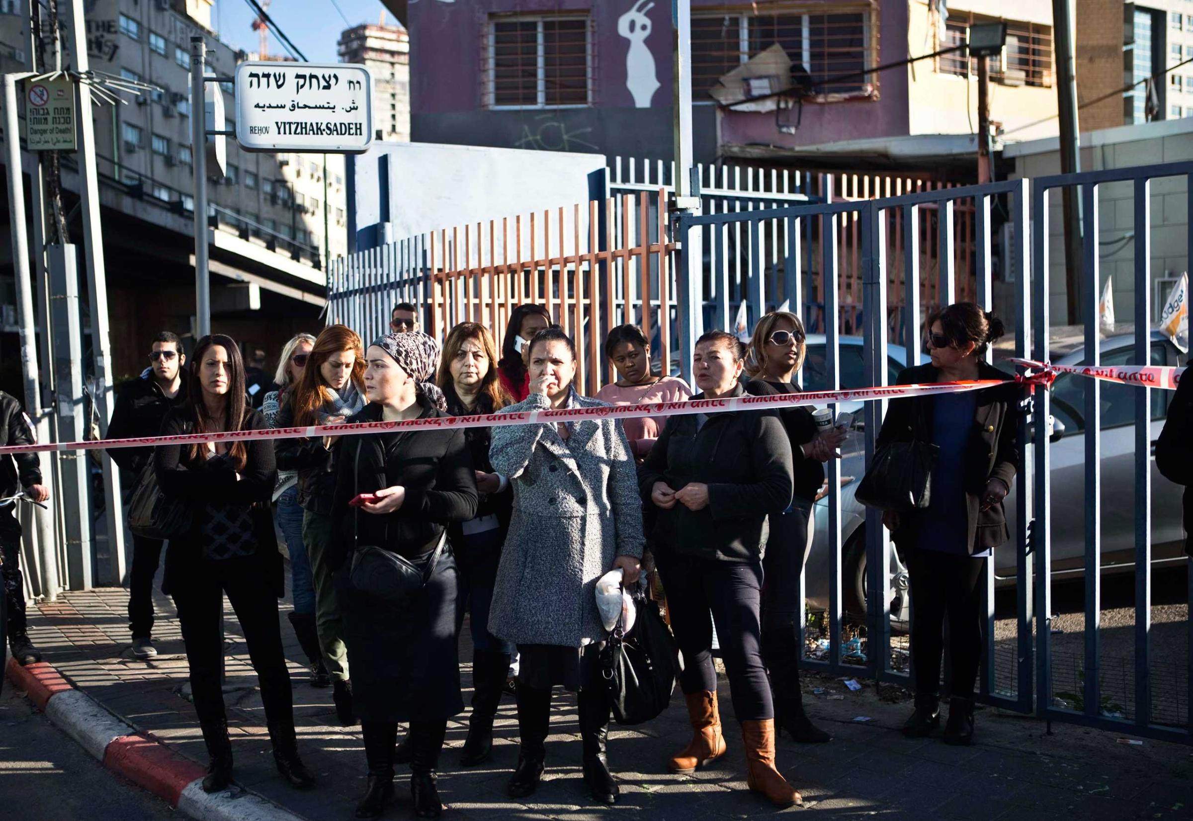 Passers-by stand behind a police tape at the scene of a stabbing attack in Tel Aviv, Jan. 21, 2015.