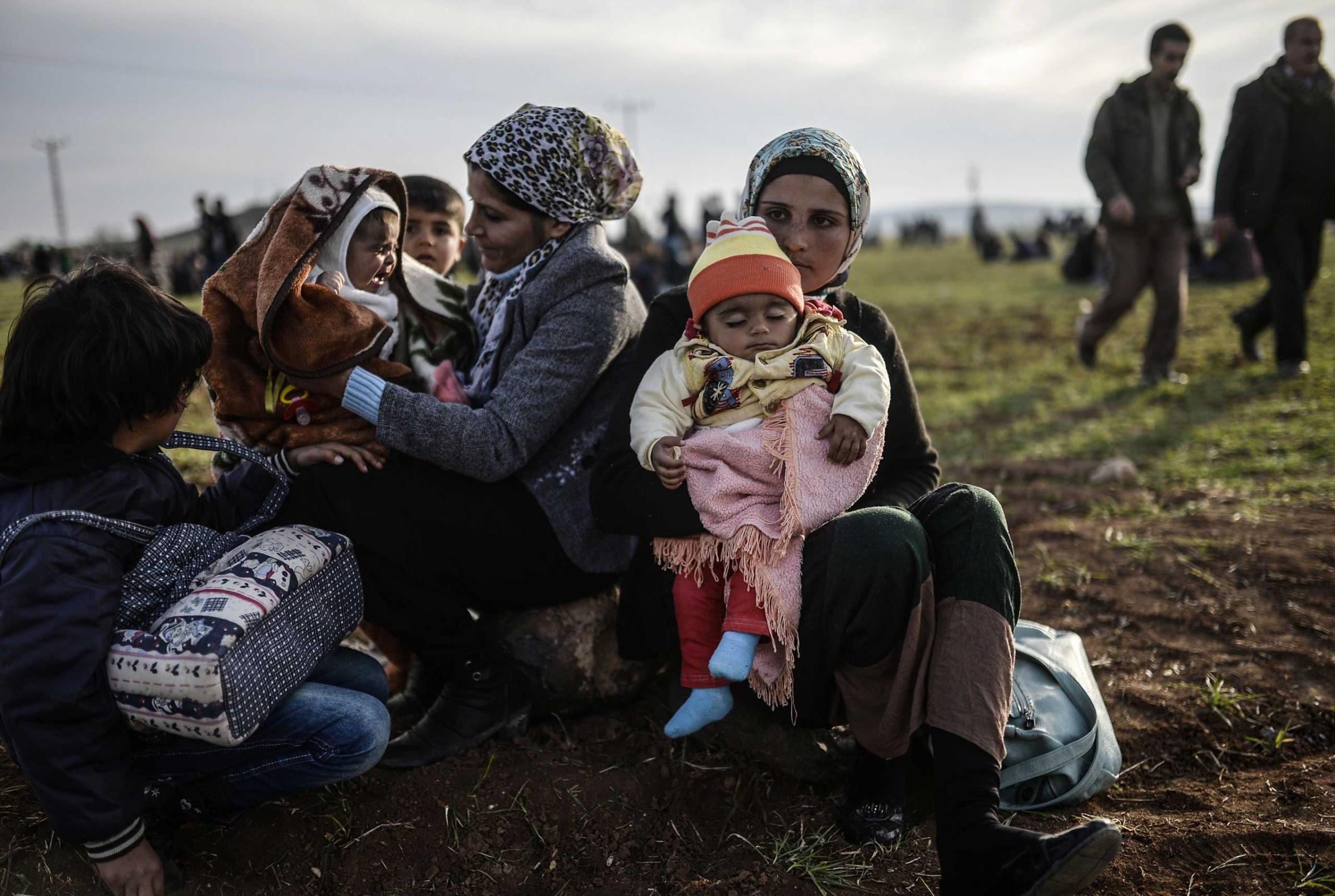 Syrian Kurdish women sit with their children near the Turkish-Syrian border in Suruc, Jan. 27, 2015.