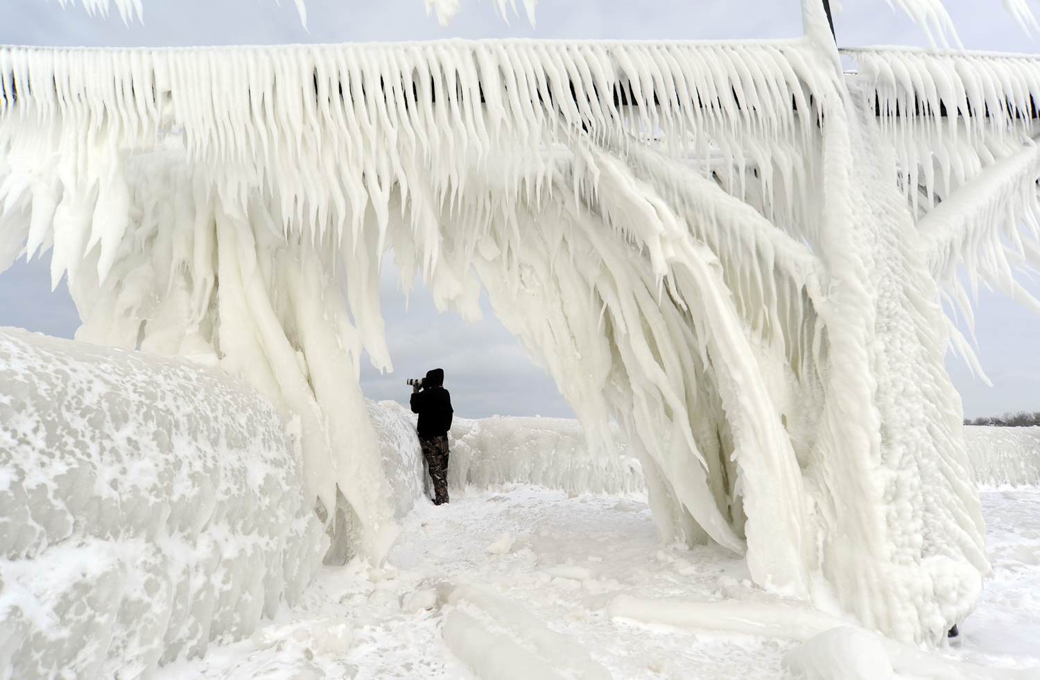 Ice coats the railings leading to the North Pier Lighthouses as a photographers takes pictures on Jan. 10, 2015, in St. Joseph, Mich. (Don Campbell — AP)