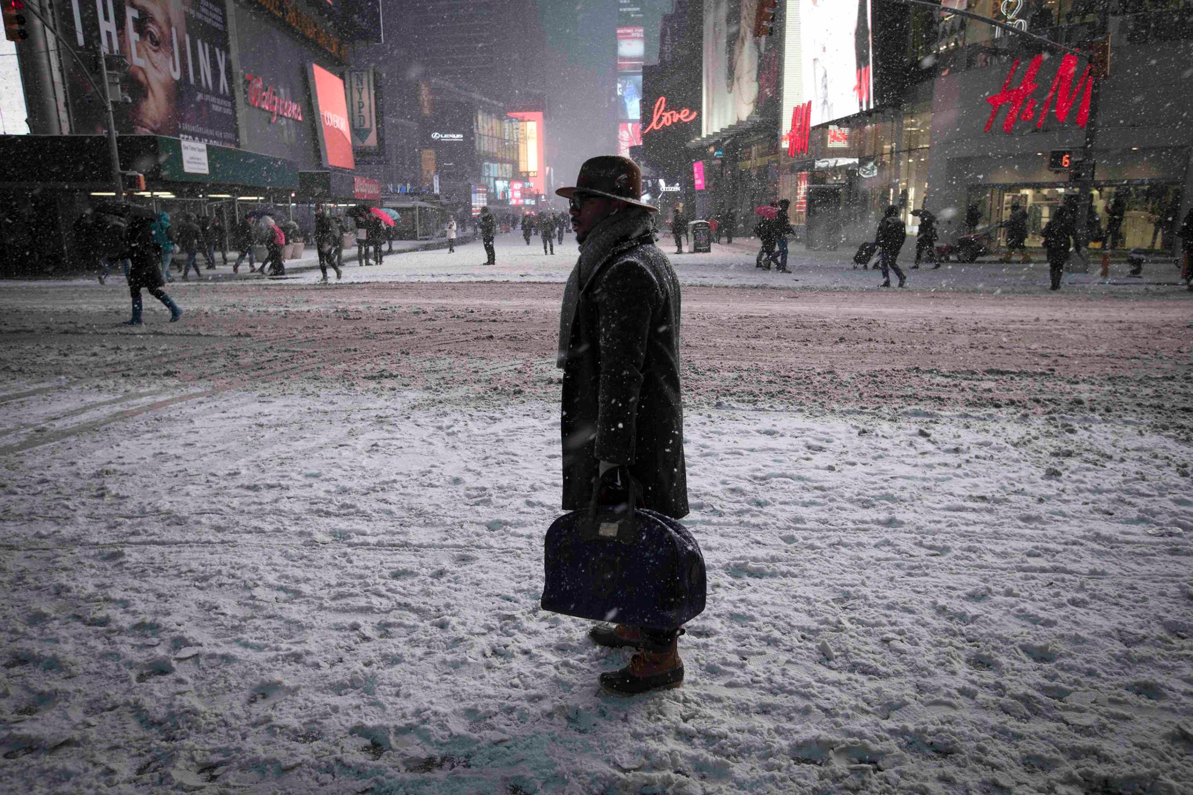 A man stands in falling snow on West 42nd street in Times Square in New York