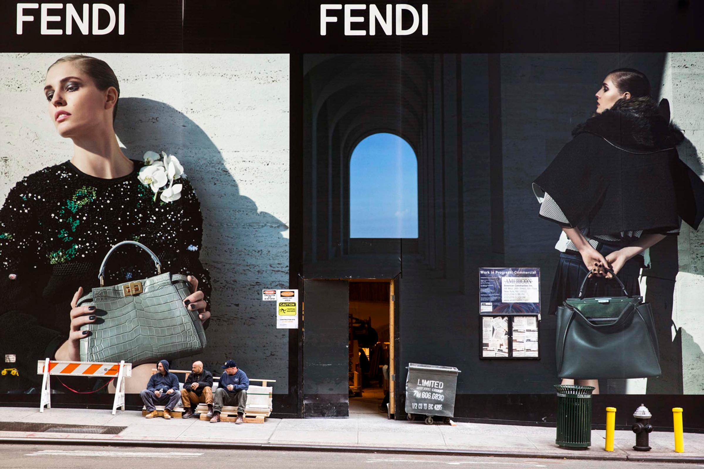 Construction workers take a break next to a Fendi billboard on 57th Street and Madison Avenue, New York, Oct 30, 2014.
