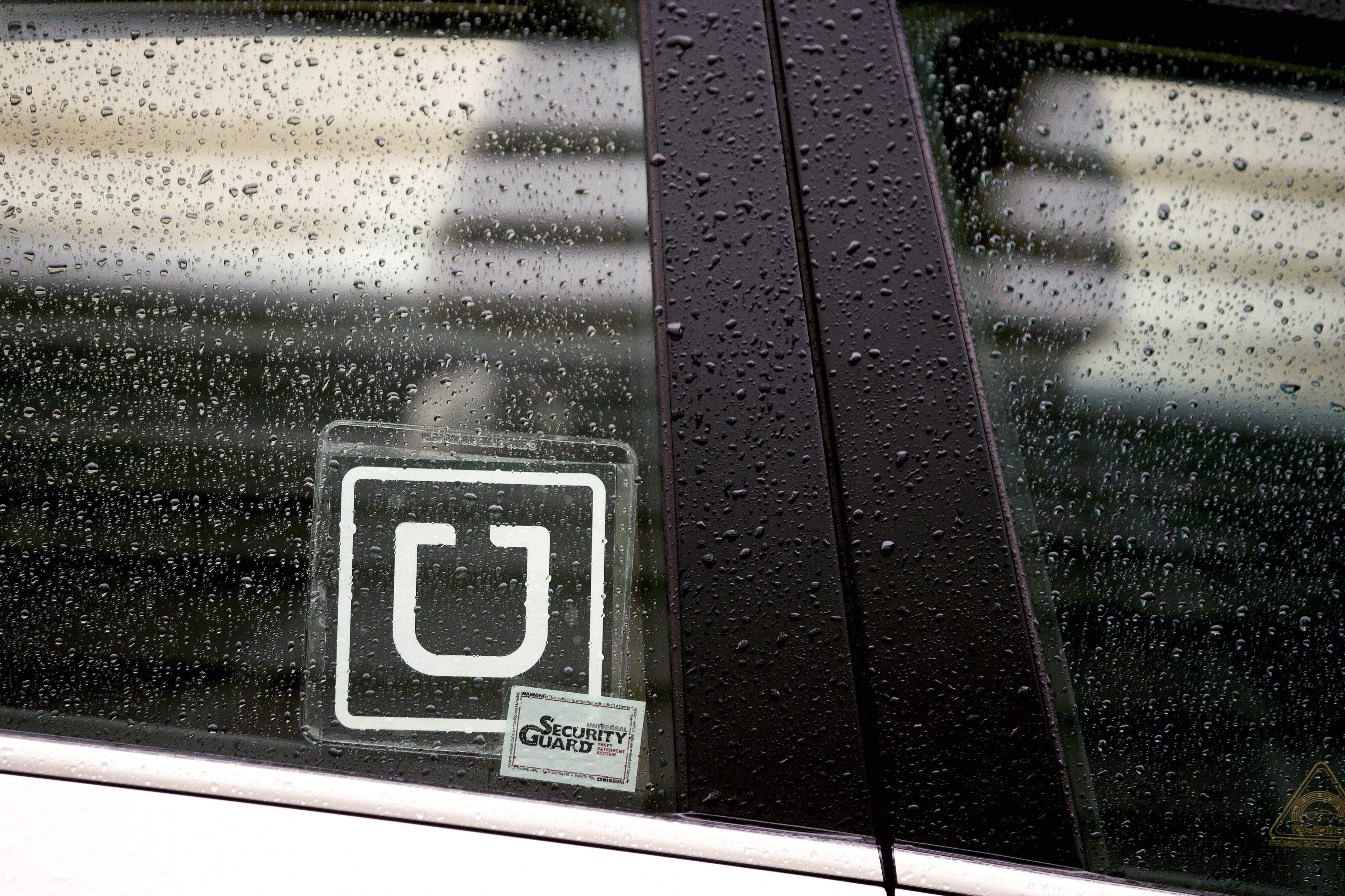 The Uber Technologies Inc. logo is displayed on the window of a vehicle after dropping off a passenger at Ronald Reagan National Airport (DCA) in Washington on Nov. 26, 2014. (Bloomberg/Getty Images)