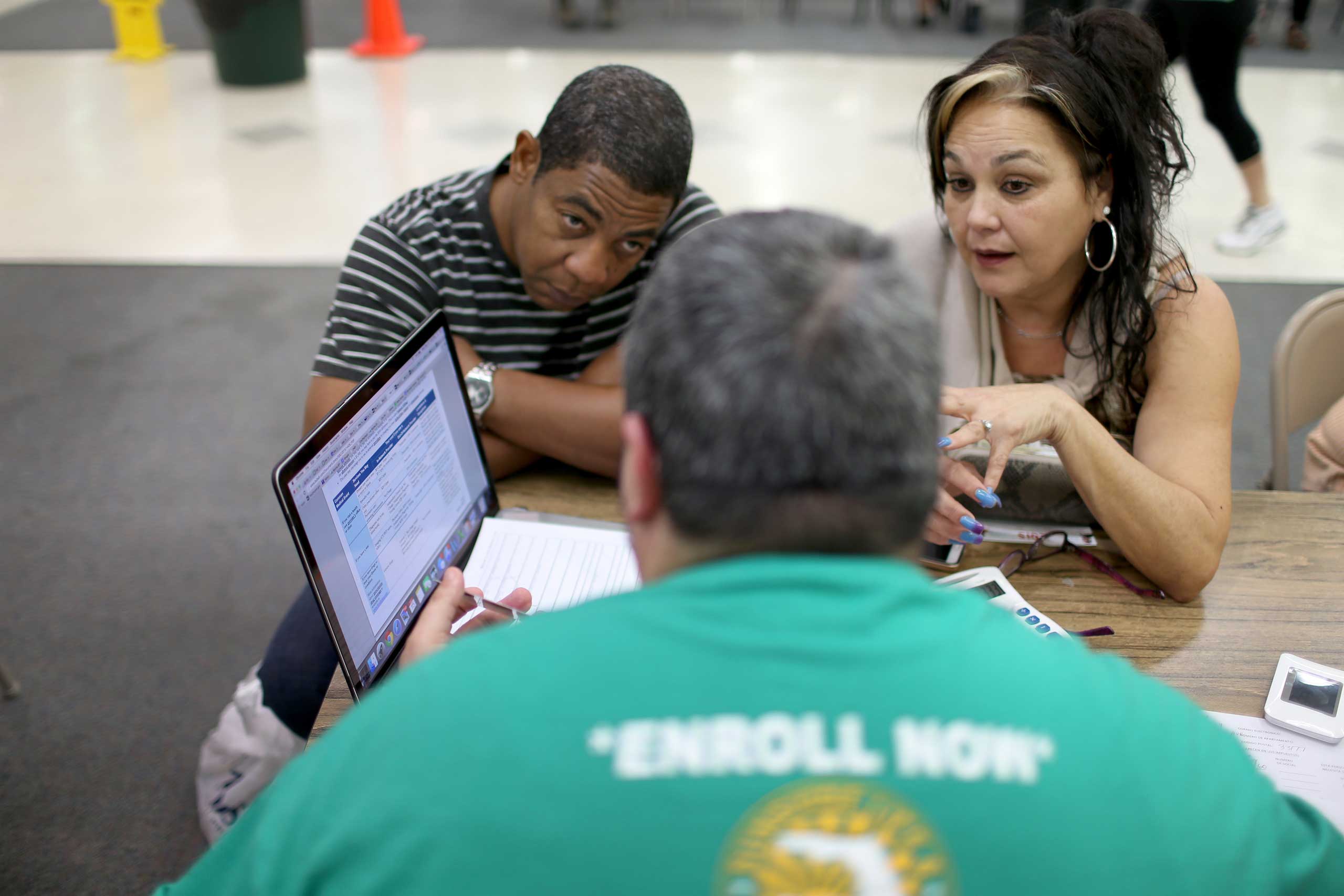 Jose Ramirez, left, and Mariana Silva speak with Yosmay Valdivia, an agent from Sunshine Life and Health Advisors, as they discuss plans available from the Affordable Care Act in the Mall of the Americas on Dec. 15, 2014 in Miami. (Joe Raedle—Getty Images)