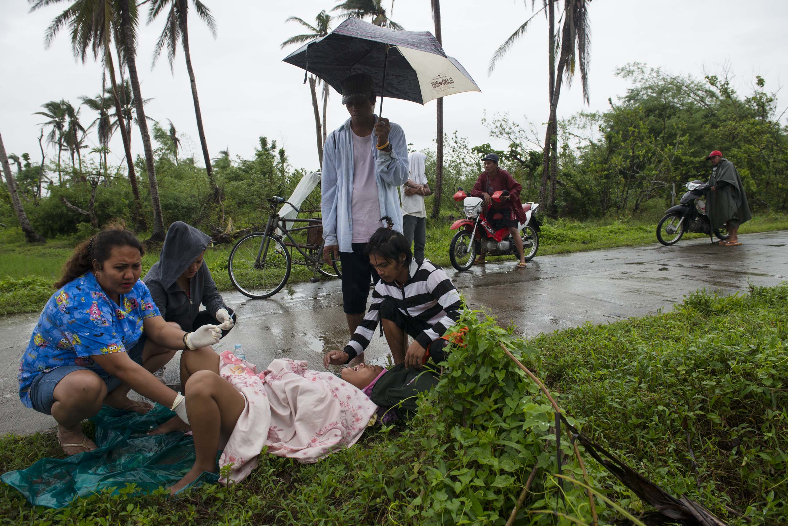 Jan. 11, 2014: Midwife Norina Malate delivers the baby of Analyn Pesado, 18, as Analyn's partner, Ryan Bacate, 21, looks on at the side of the road en route to the nearest clinic in Tolosa, outside of Tacloban, in the Philippines.