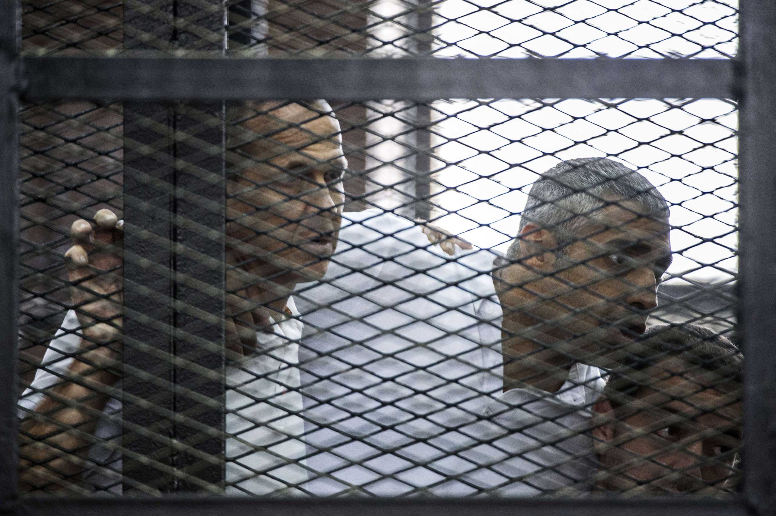 Al-Jazeera news channel's Australian journalist Peter Greste (L) and his colleagues, Egyptian-Canadian Mohamed Fadel Fahmy (C) and Egyptian Baher Mohamed, listen to the verdict inside the defendants cage during their trial at Tora prison in Cairo on June 23, 2014. (Khaled Desouki—AFP/Getty Images)