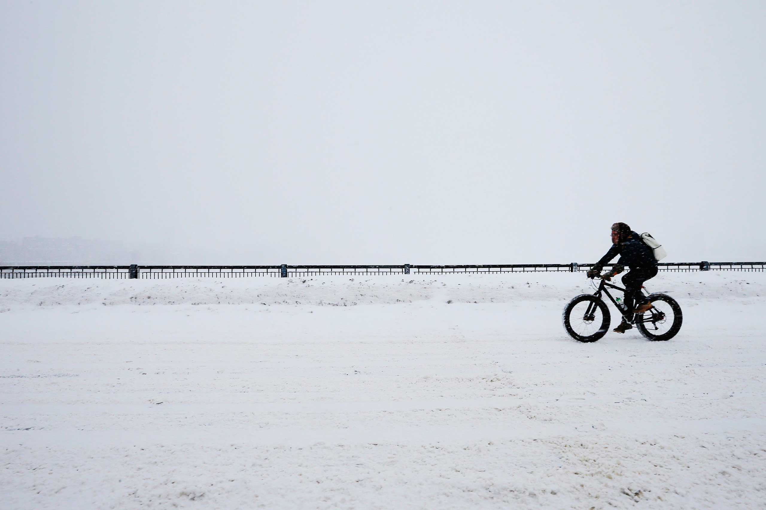 A cyclist rides across the Mass Ave bridge during a winter snow storm in Boston on Feb. 9, 2015.