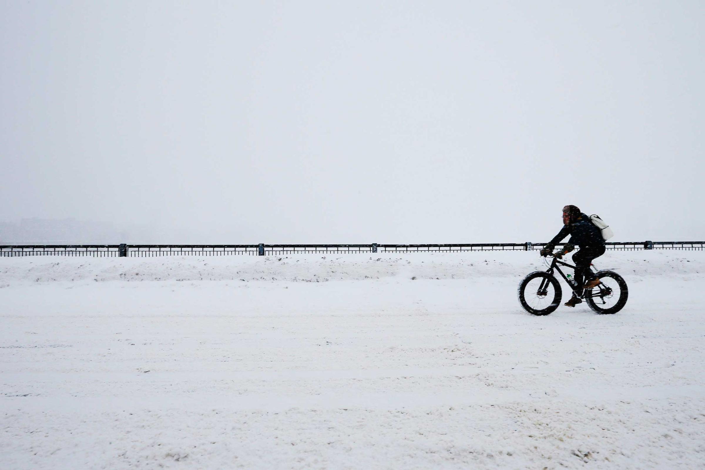 A cyclist rides across the Mass Ave bridge during a winter snow storm in Boston