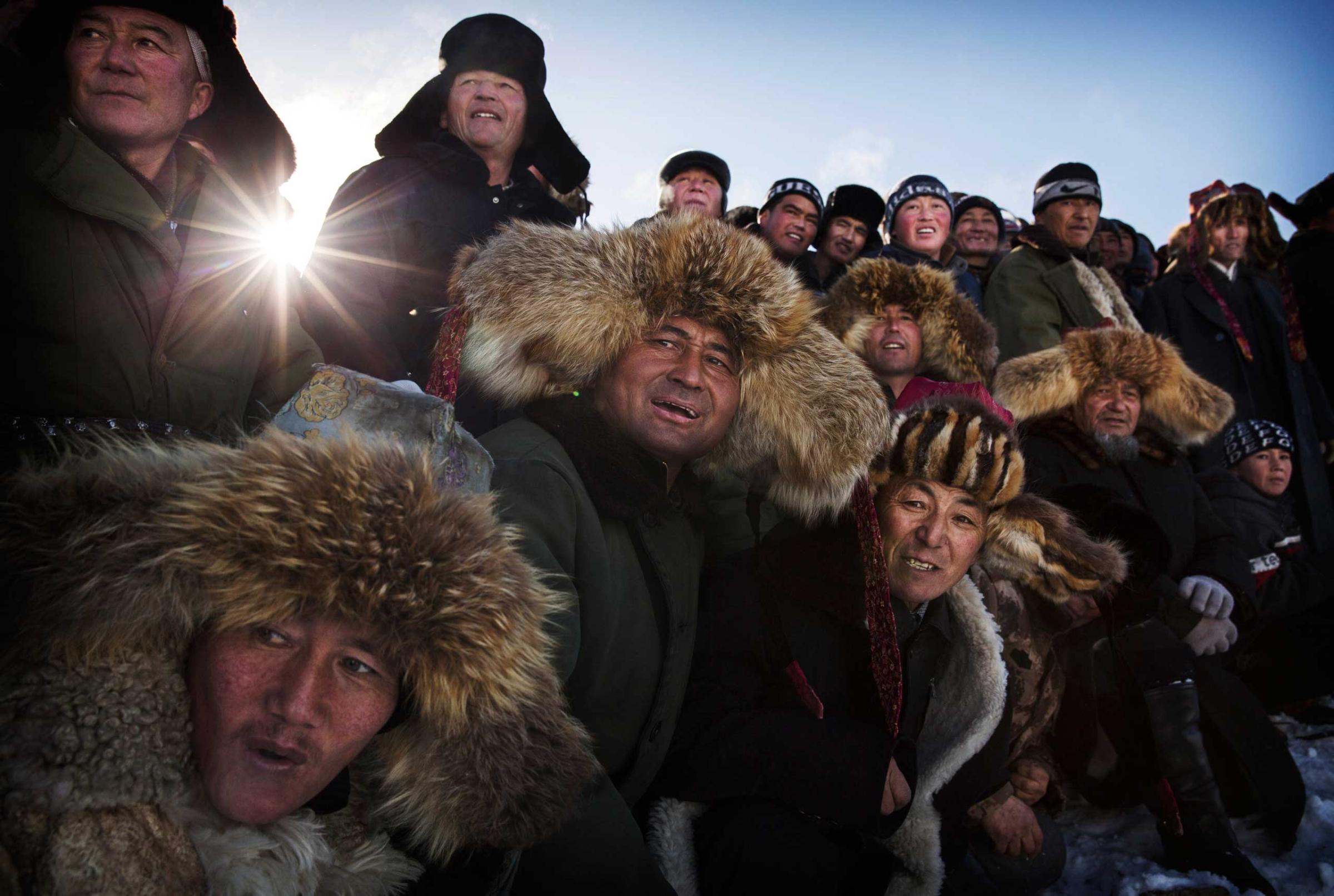 Spectators react as they watch a Chinese Kazakh eagle hunter, not seen, release his bird during a local competition.