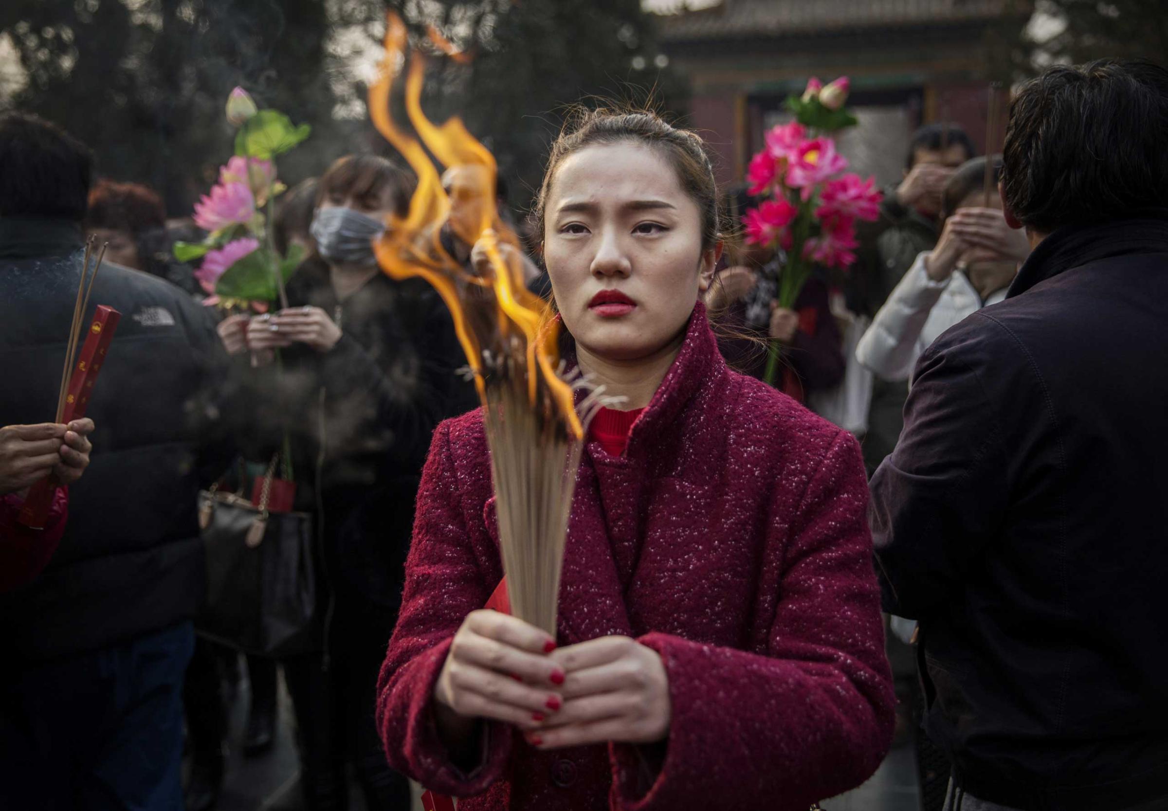 Chinese woman holds incense while praying with others at the Yonghegong Lama Temple during celebrations for the Lunar New Year, Feb. 19, 2015 in Beijing.