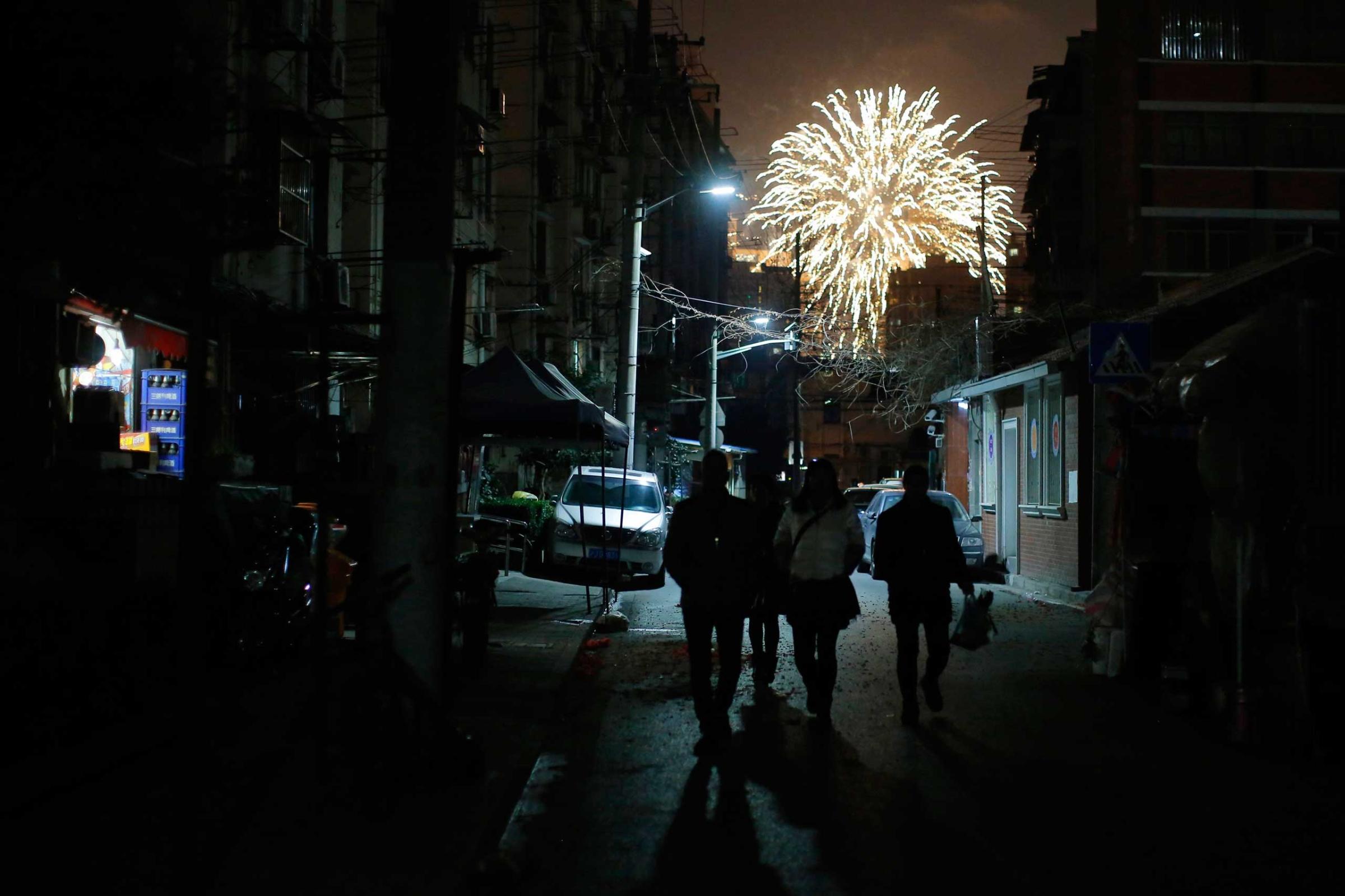 People walk as residents set off fireworks as part of Chinese New Year celebrations in Shanghai, Feb. 19, 2015.